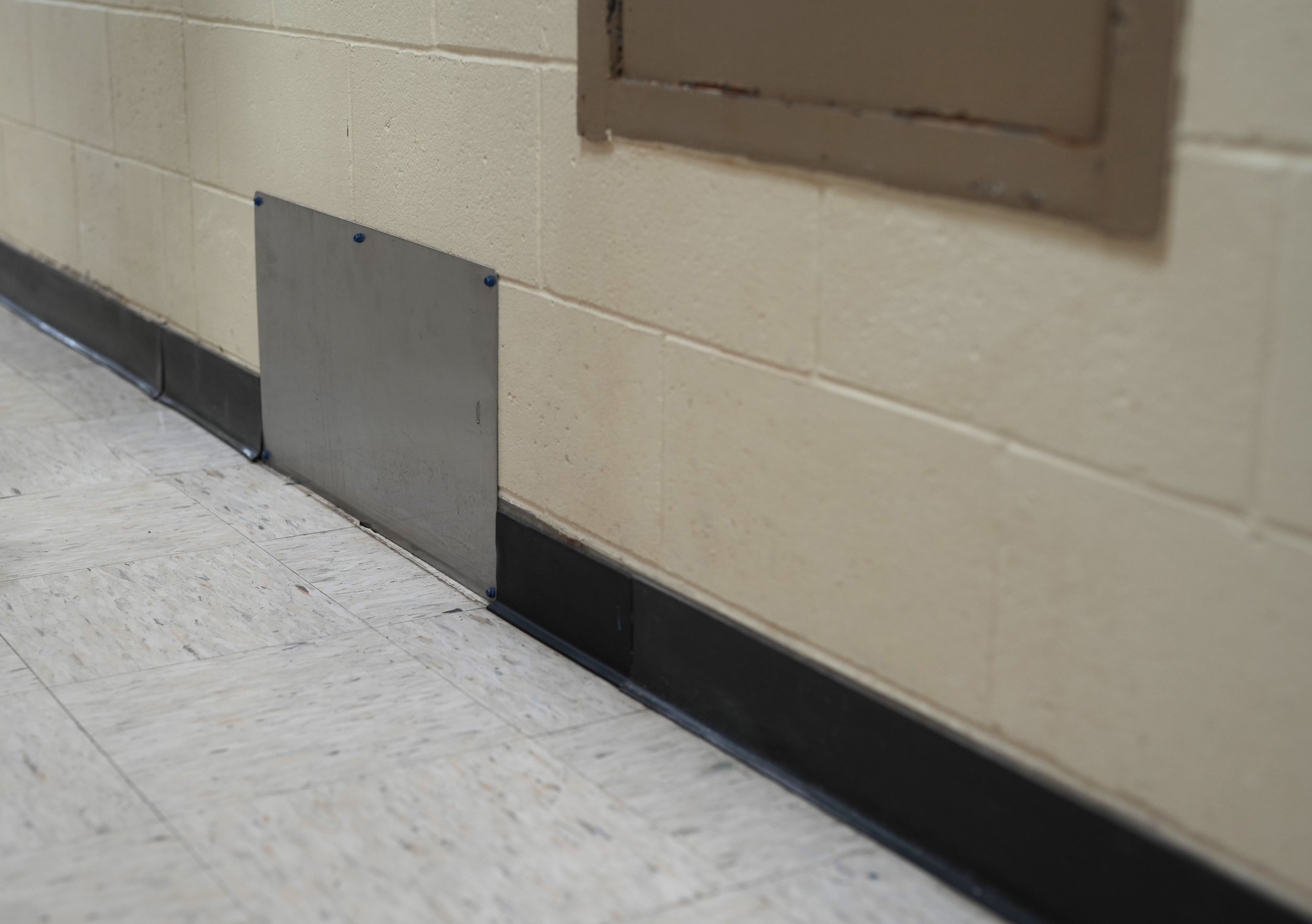 Due to frequent plumbing work, part of the wall was cut out and replaced with a steel panel to allow recurring access if needed.