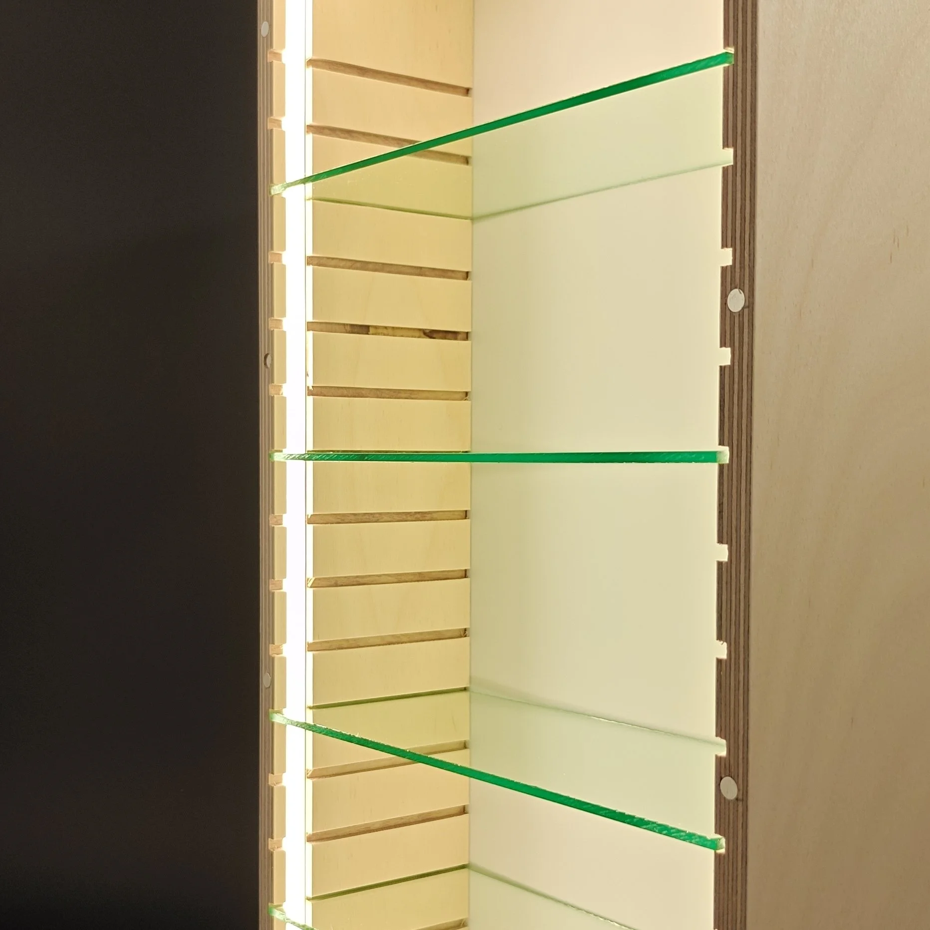 The image shows a room divider or display rack with multiple horizontal beige or light-colored panels separated by vertical wooden supports. There are green rods on either side of the panels, possibly for holding or supporting something, and the setup is illuminated by bright lighting, creating distinct shadows and highlights on the panels.