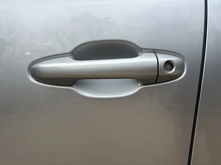 Close-up of a silver car door handle on a silver vehicle.