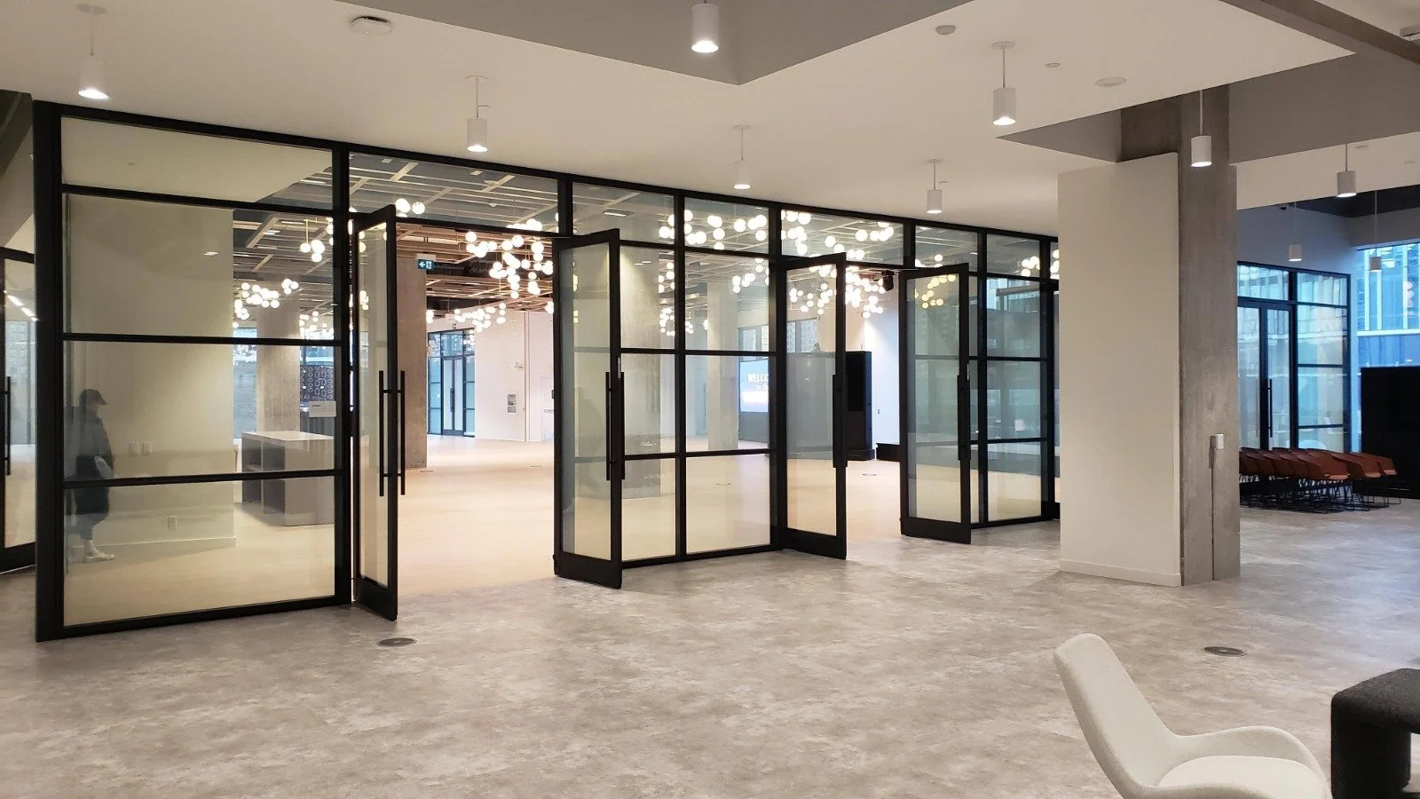 Empty modern lobby or waiting area with glass doors, large windows, and contemporary lighting fixtures.
