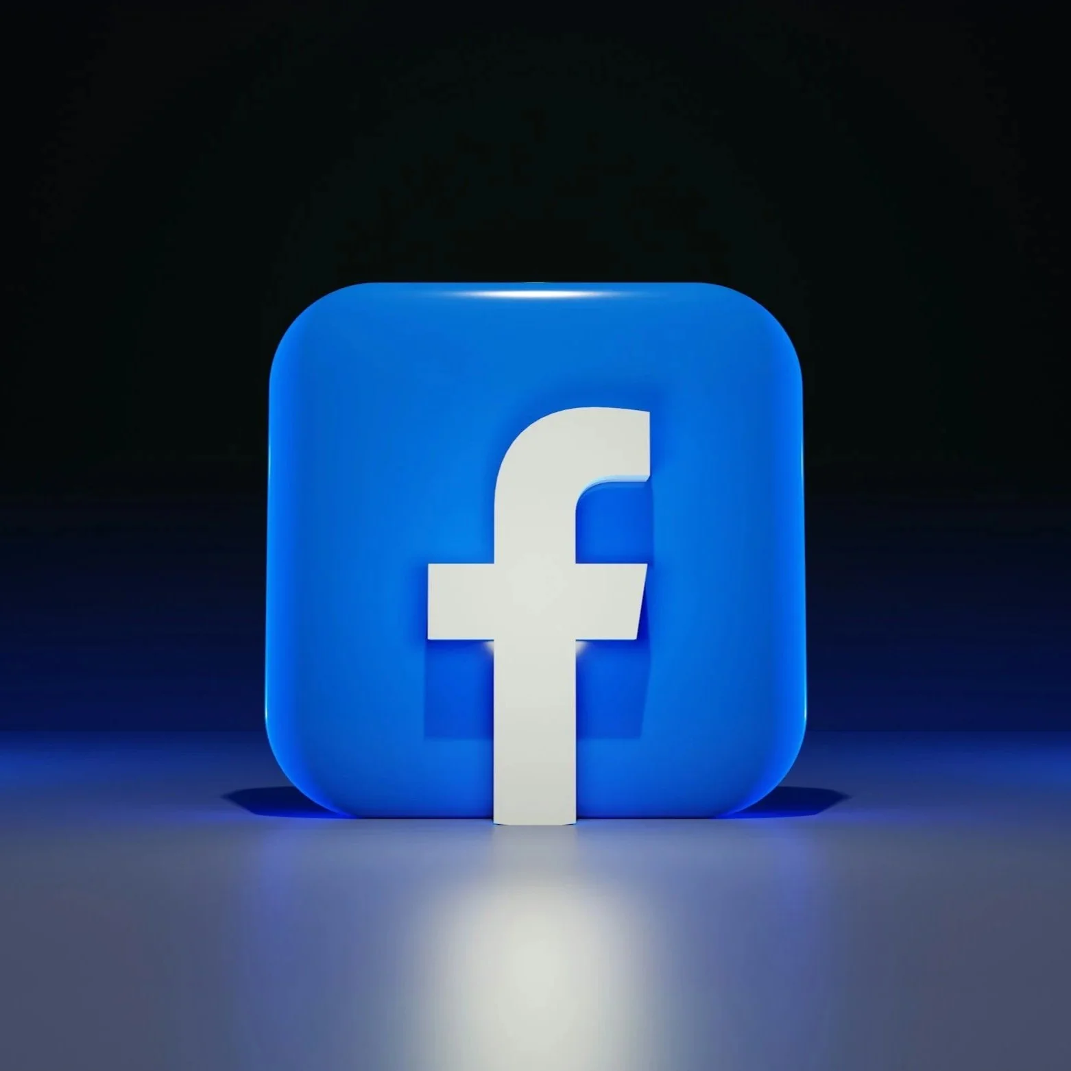 3D Facebook logo illuminated in blue light on dark background.