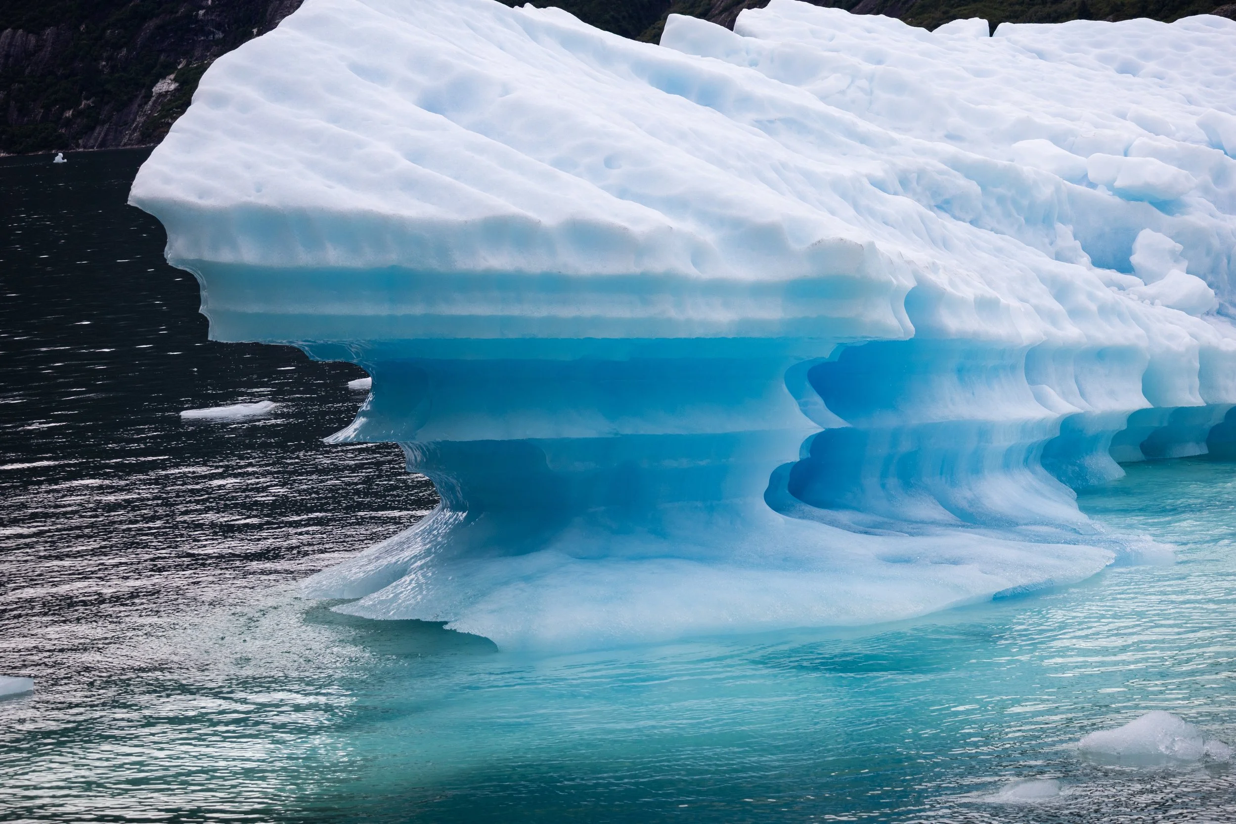 Large, layered iceberg floating in cold Alaskan ocean water