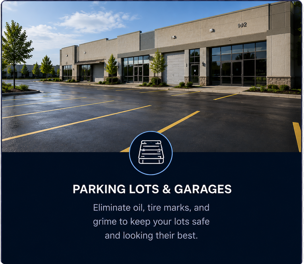 Empty parking lot with a commercial building in the background; sign promoting parking lot and garage maintenance to remove oil, tire marks, and grime.