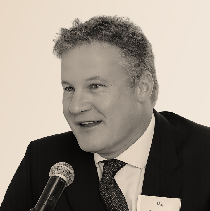 A man in a suit and tie speaking into a microphone.