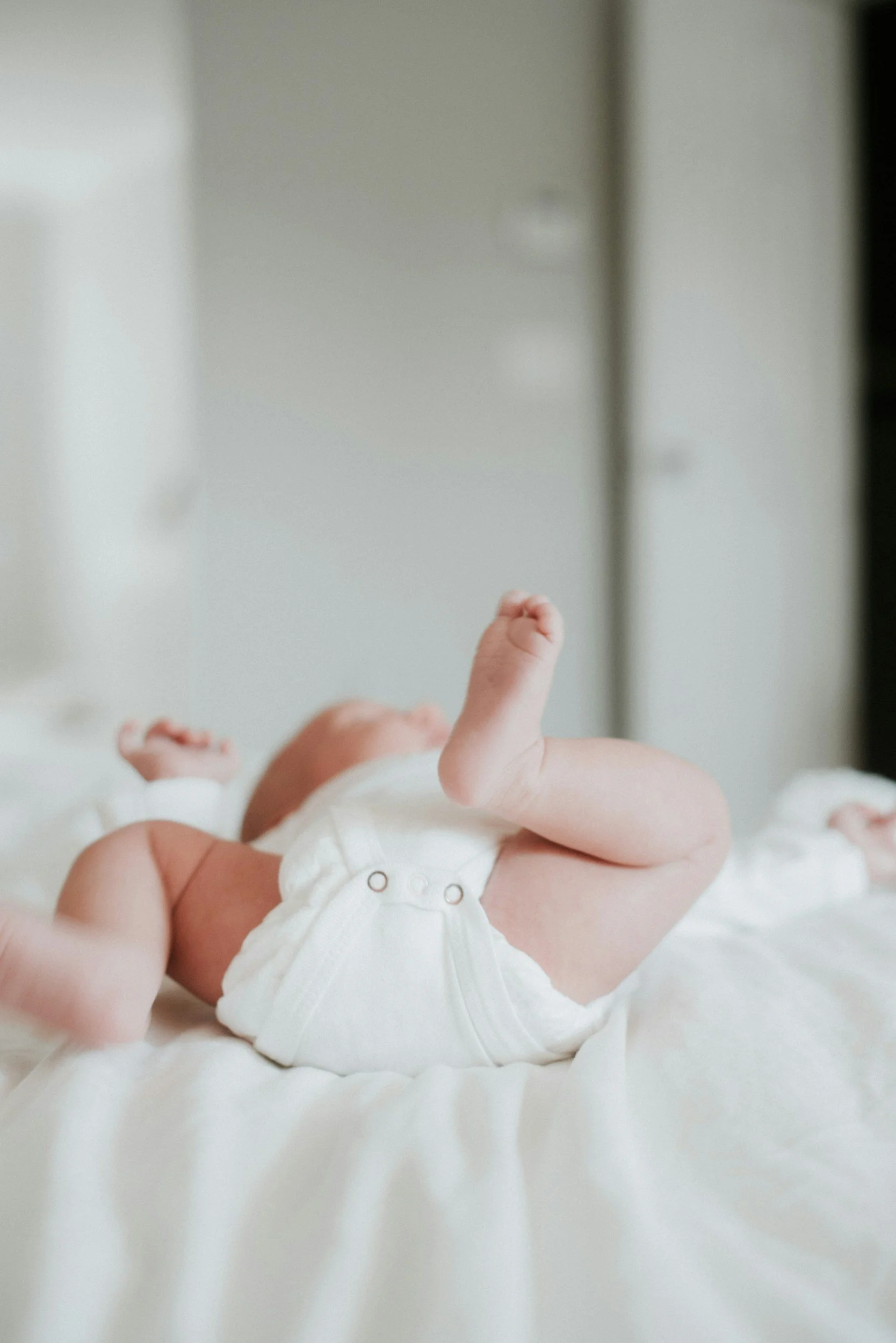 A baby lying on a white blanket in Redmond Oregon after a calm infant massage practice promoting connection and soothing care.