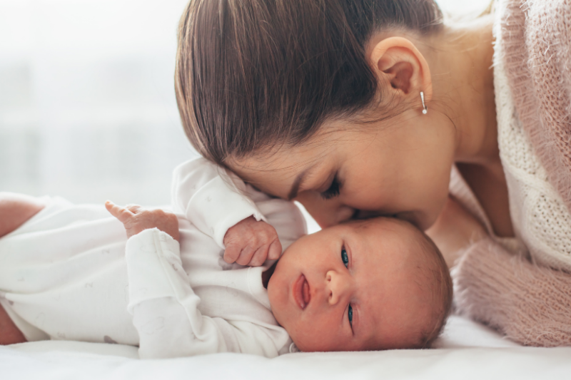 A woman lovingly kissing a newborn baby on the forehead after her virtual lactation visit from a Redmond lactation specialist