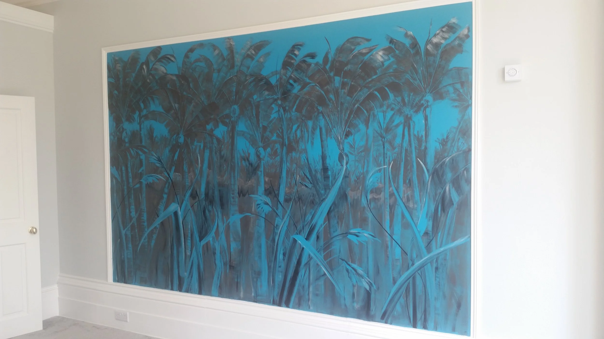 Interior wall with a large mural of tall grass and tropical trees painted in shades of blue and grey.