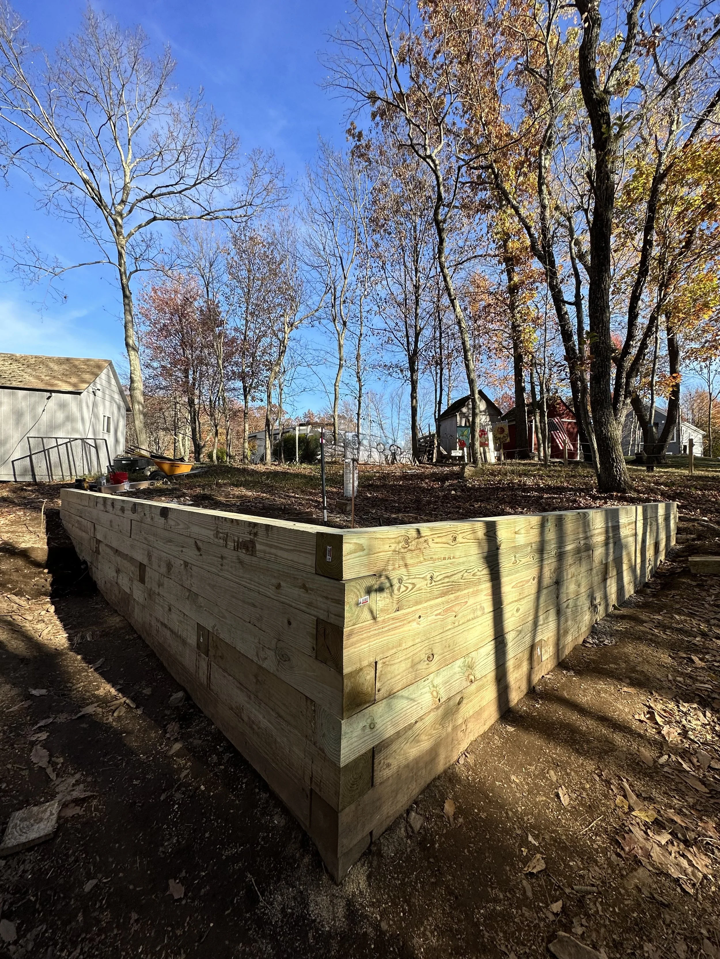 Wooden frame foundation in wooded area with trees and houses in background.