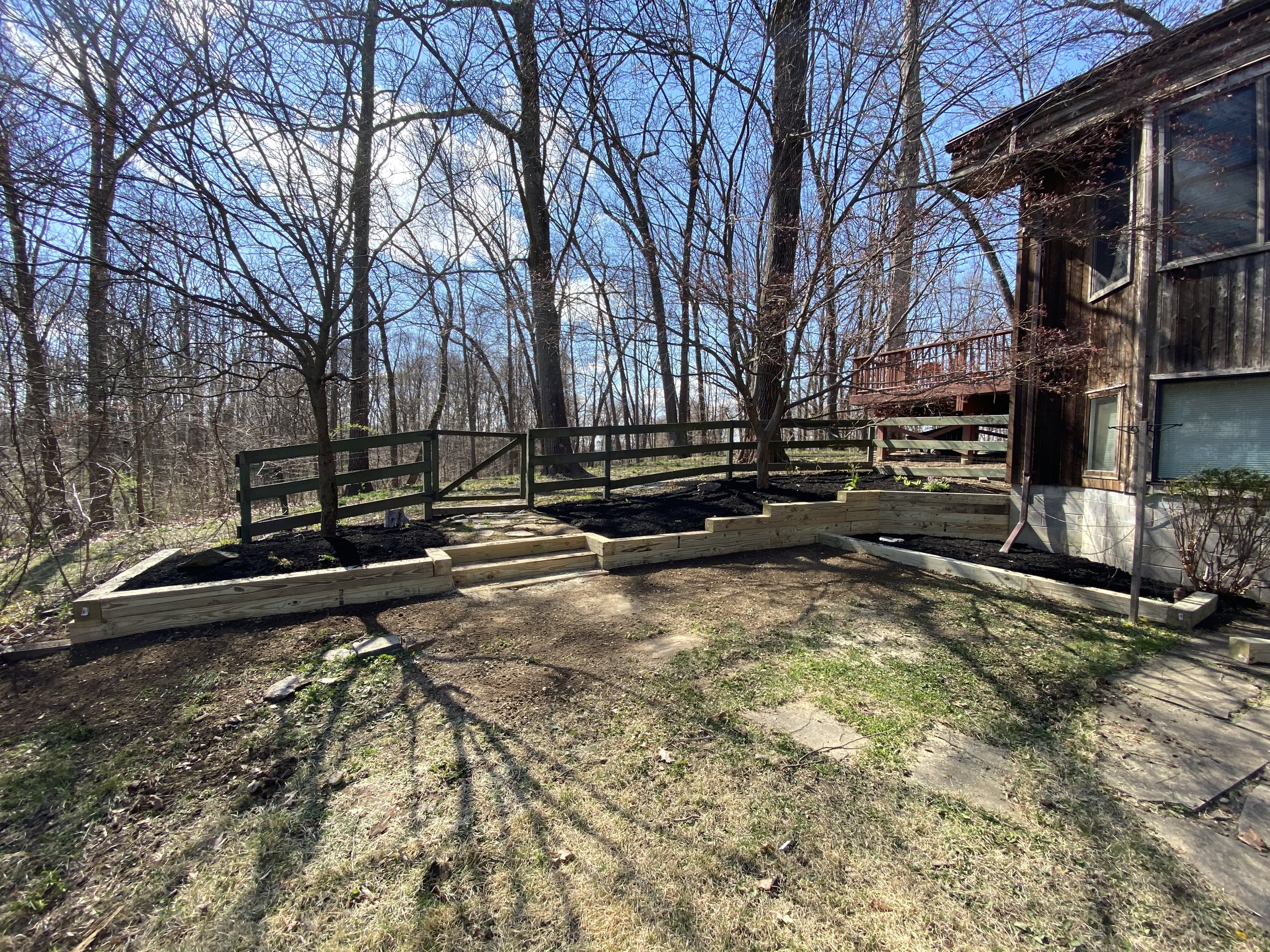 Residential backyard with wooden retaining walls and trees