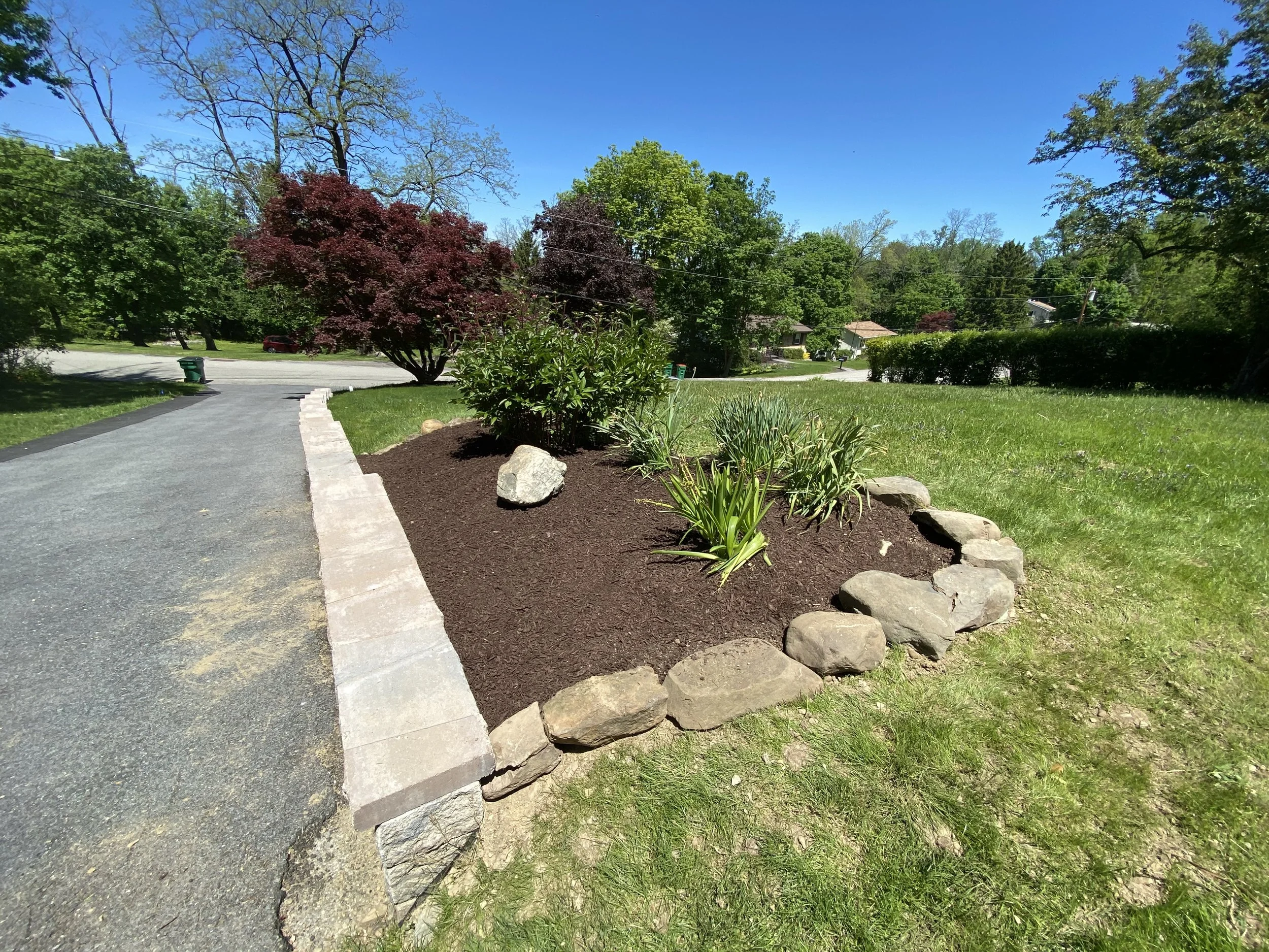 Driveway with stone wall and landscaped garden bed