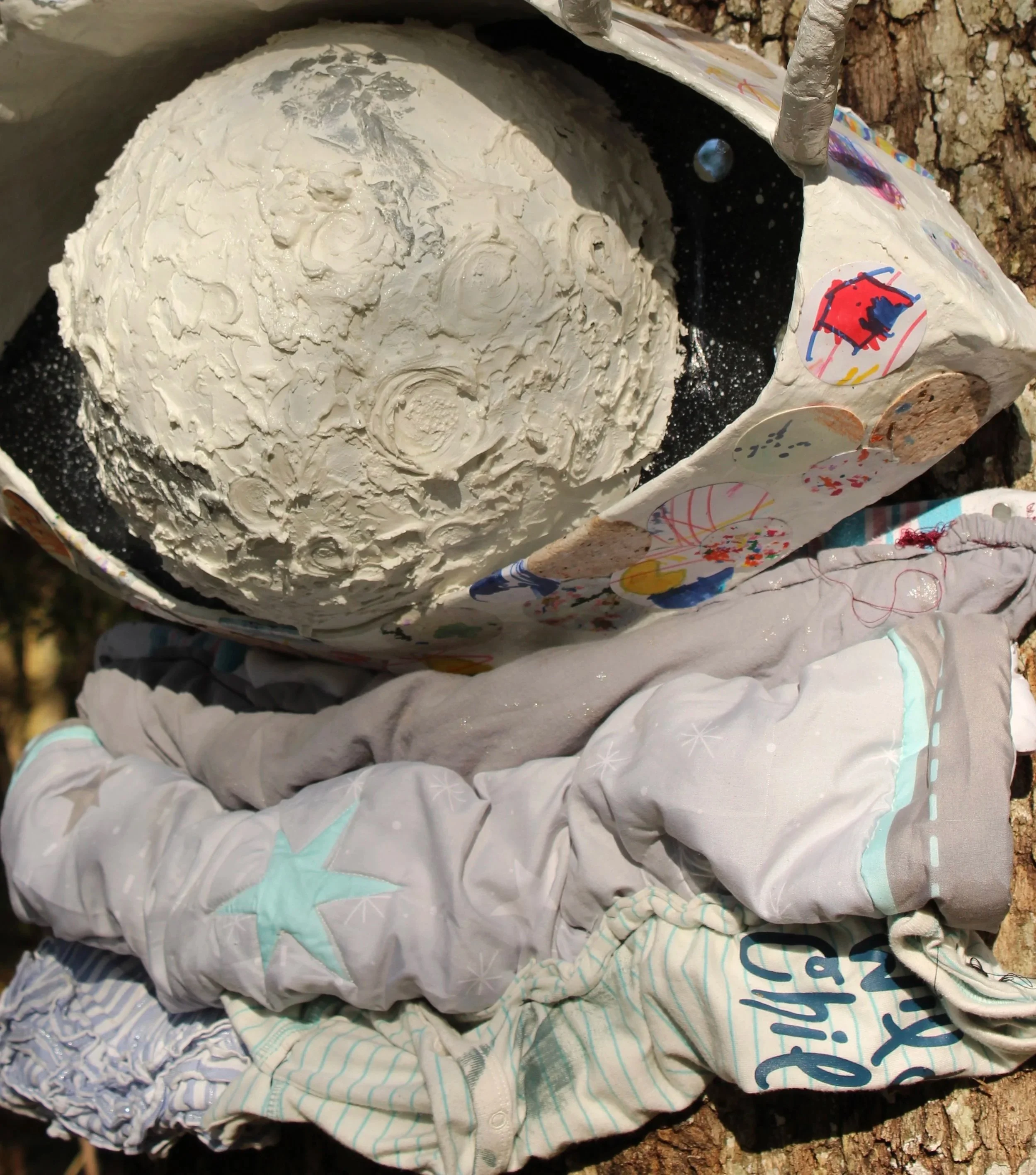 Title: A Mother’s Perspective:
,
This mixed-media sculptural work takes the form of a large eye—its gaze constructed from circular cutouts of artwork and handmade paper created in collaboration with a child over the course of two years. The piece was