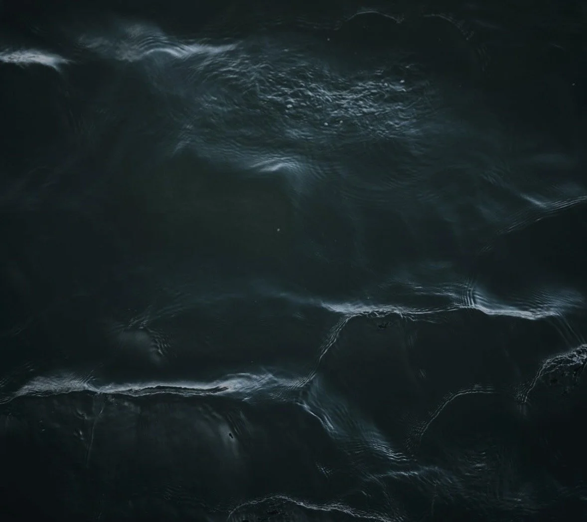 Close-up view of dark, choppy ocean waves with white splashes and ripples.