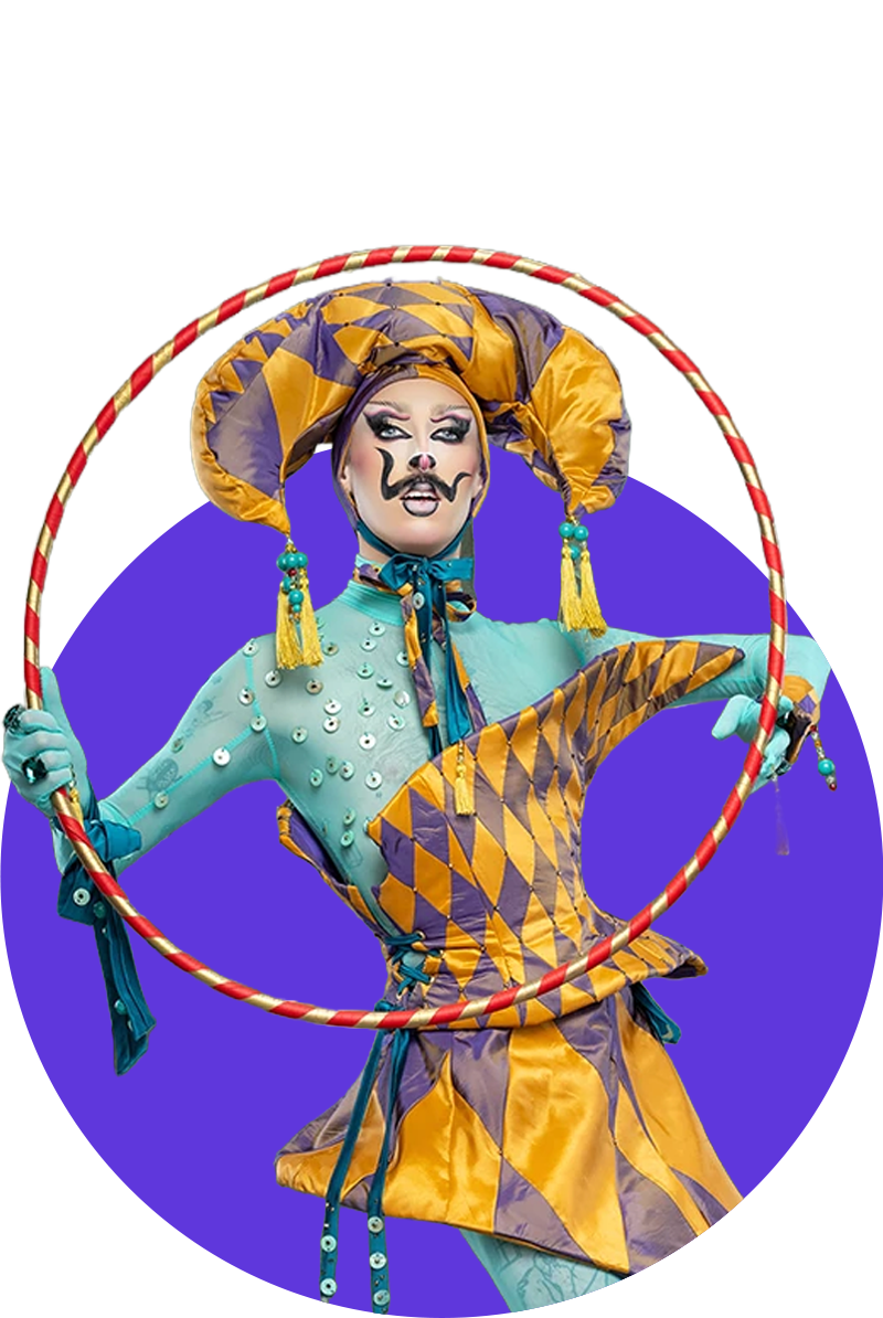 A person in colorful, theatrical clown costume with face paint, holding a juggling hoop.