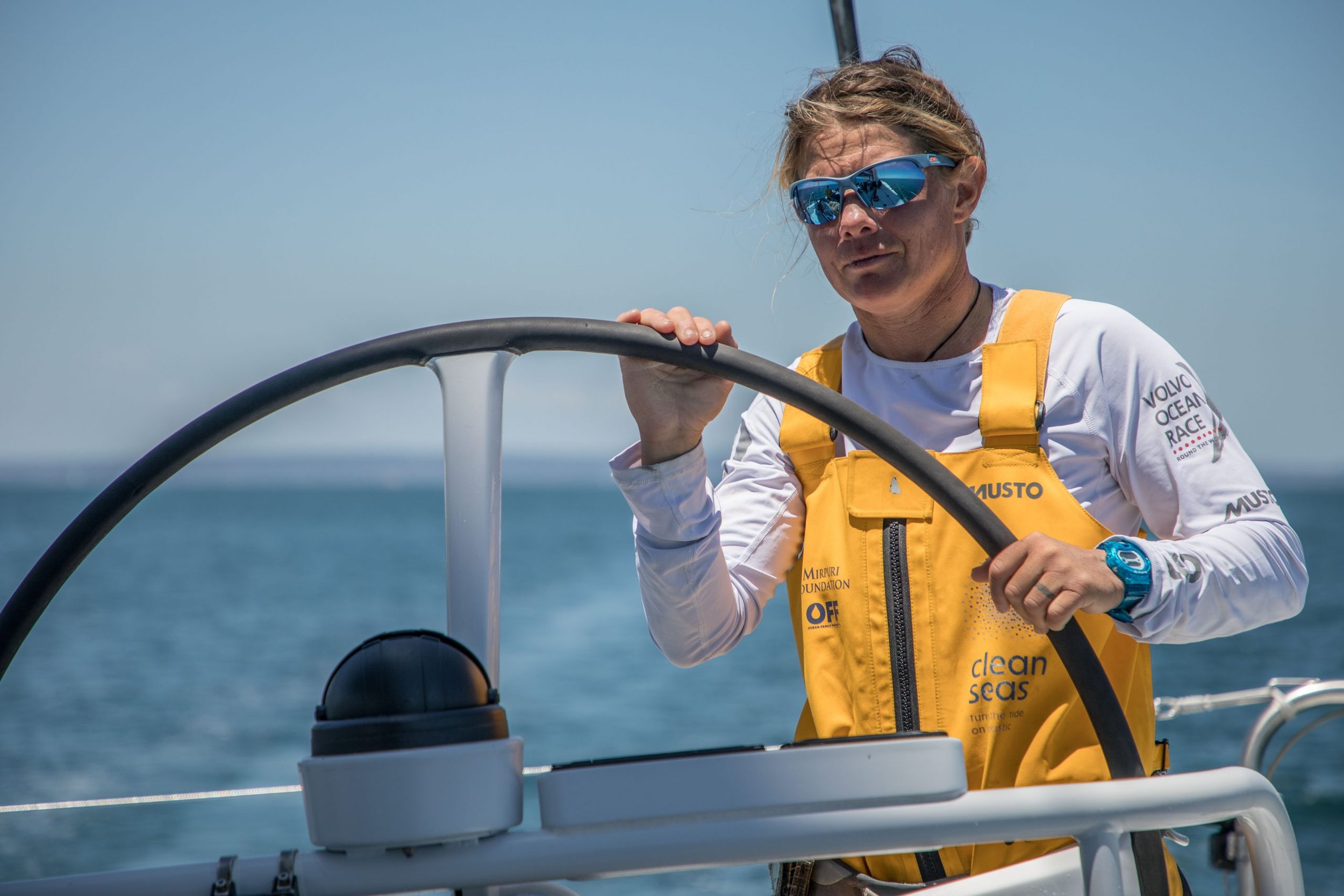 Professional sailor Liz Wardley steering an offshore racing yacht at sea.