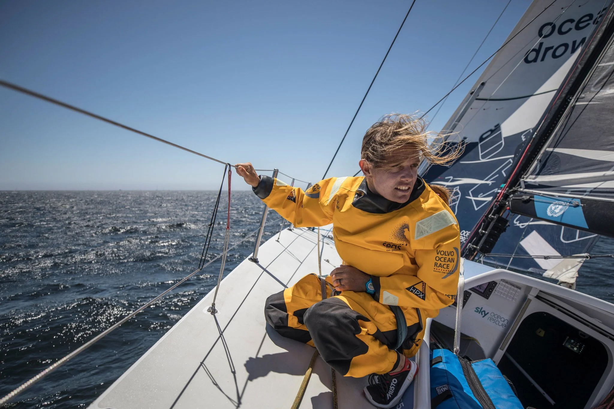 Liz Wardley working on deck aboard an offshore racing yacht in yellow waterproofs.