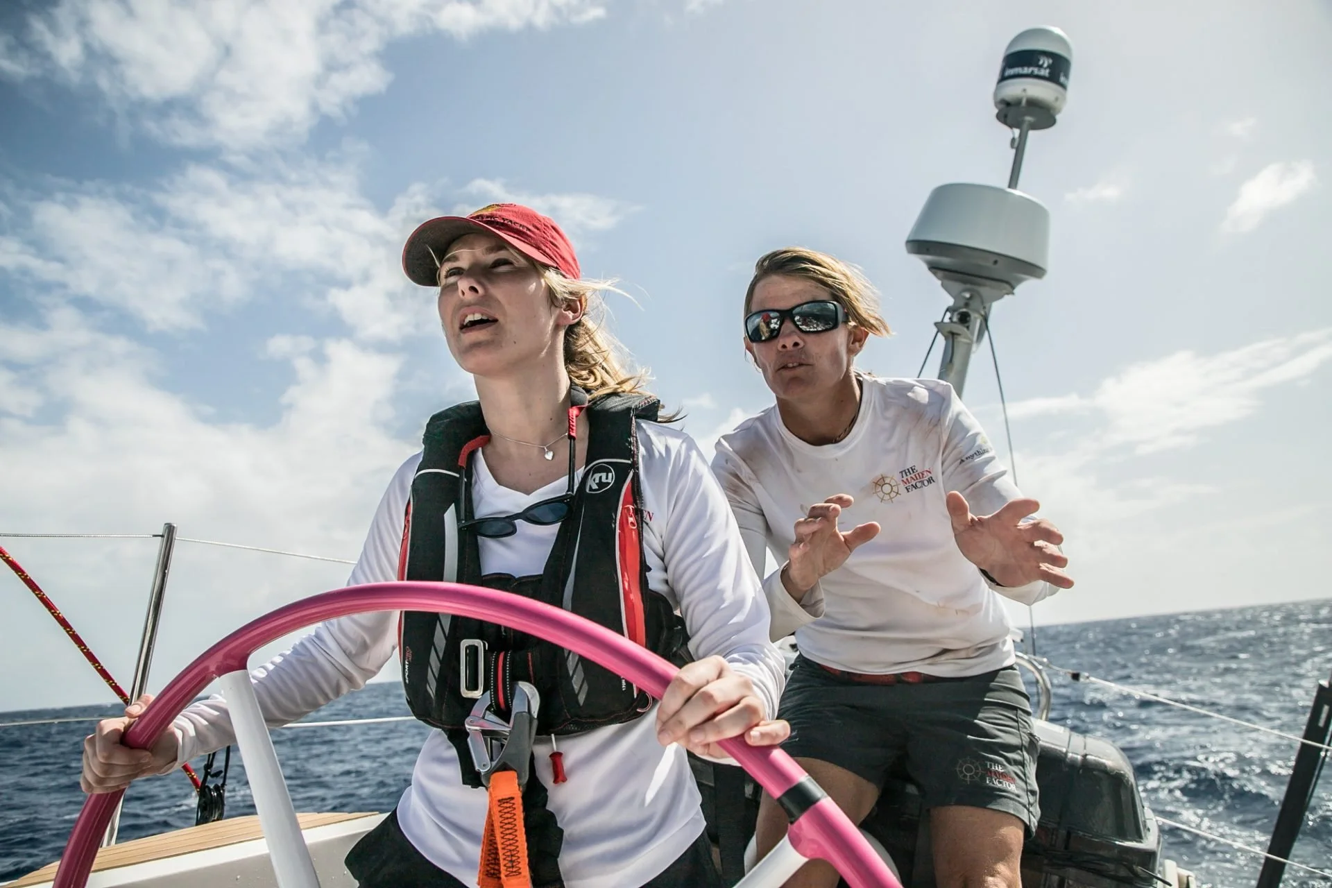 Liz Wardley steering a sailing yacht alongside a crew member.