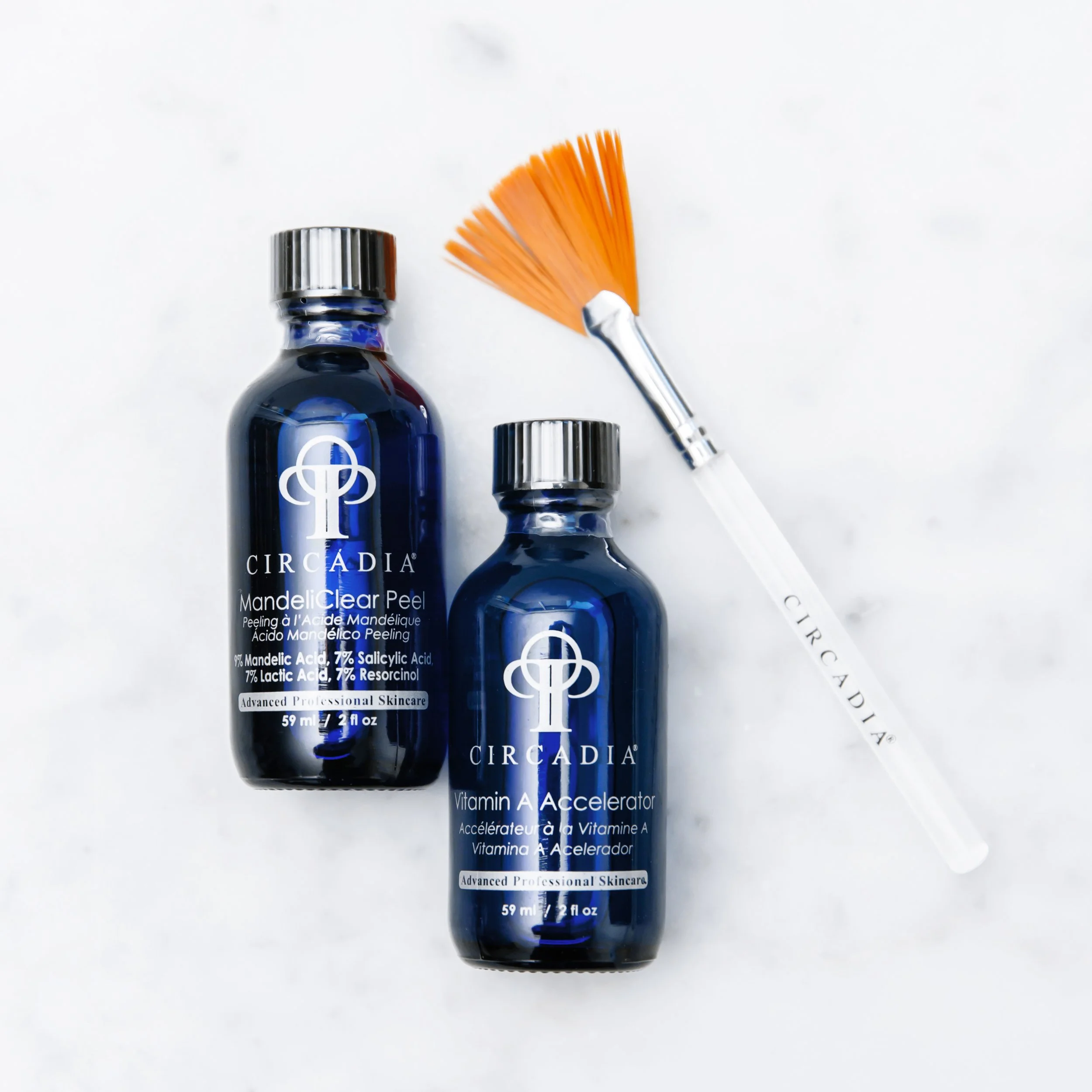 Three blue bottles of Circadia Vitamin A Accelerators with silver caps, one of which is open and has an orange fan-shaped applicator brush beside it, all on a white background.