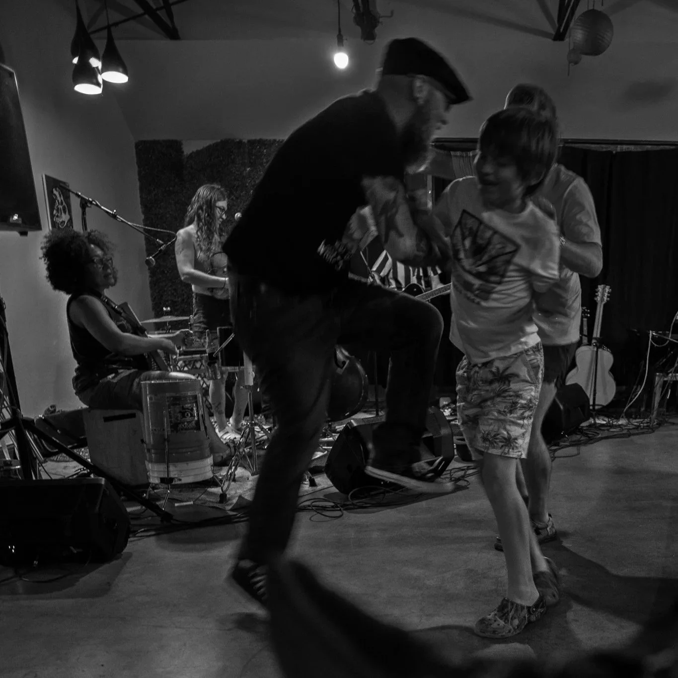 People dancing in front of a live band performing on stage in a dimly lit venue.