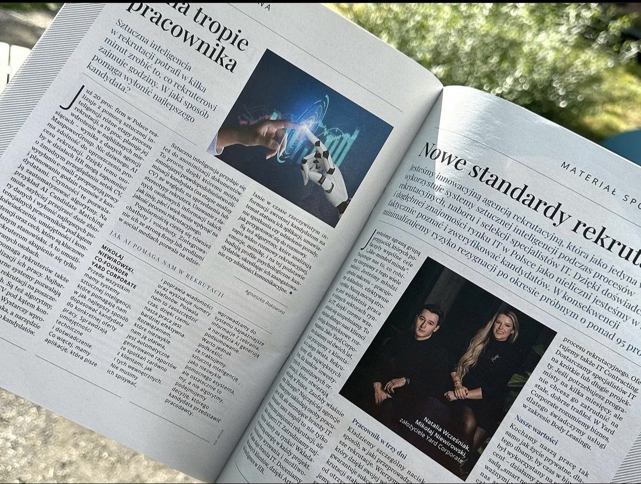 Open magazine or newspaper with articles and photos, including an image of two people sitting and a picture of a hand with a robot or robotic arm, surrounded by greenery.