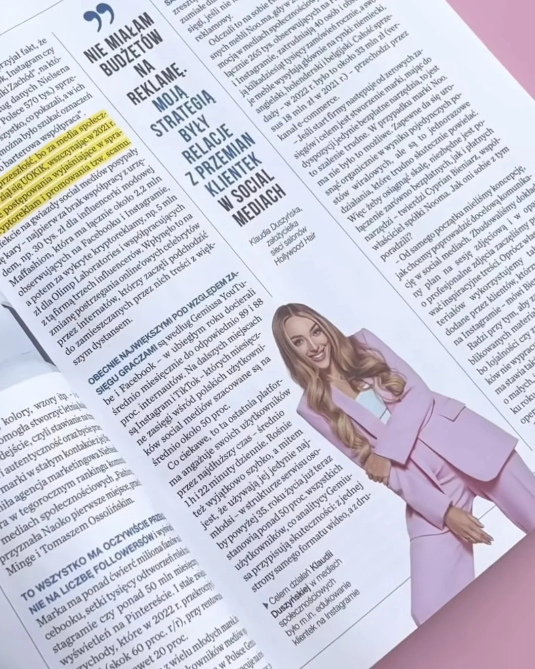 Newspaper page featuring an article with a headline in bold capital letters and a photo of a woman with long curly hair in a light pink suit, smiling and leaning slightly forward.