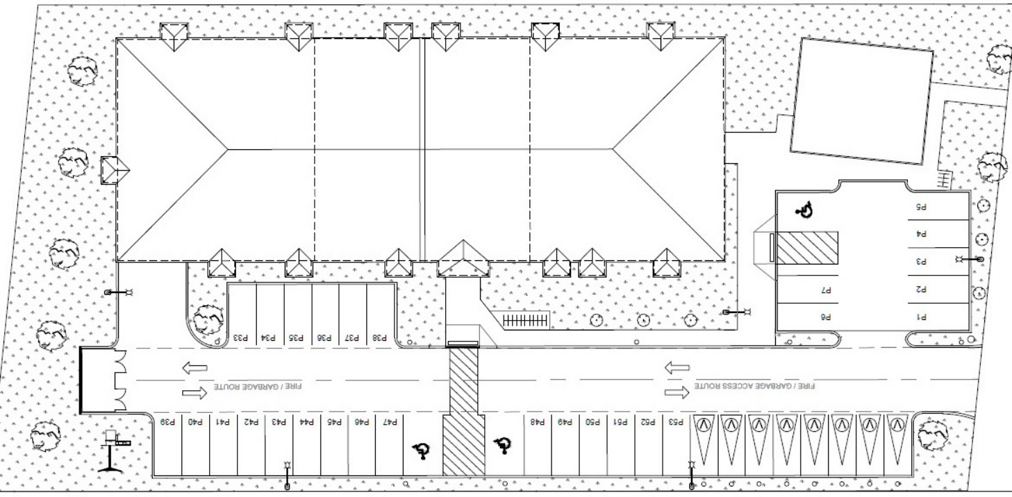 A detailed architectural site plan of a large building with parking spaces, bike racks, landscaped areas, and pathways.