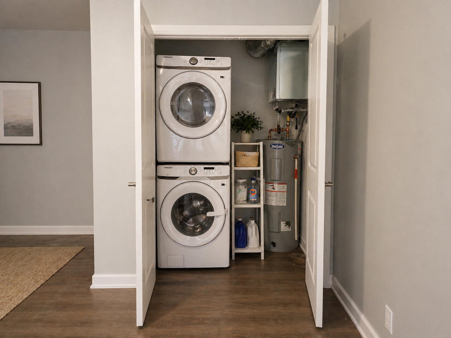 A laundry room with a stacked washing machine and dryer on the left, a water heater on the right, and an electrical panel above the heater.