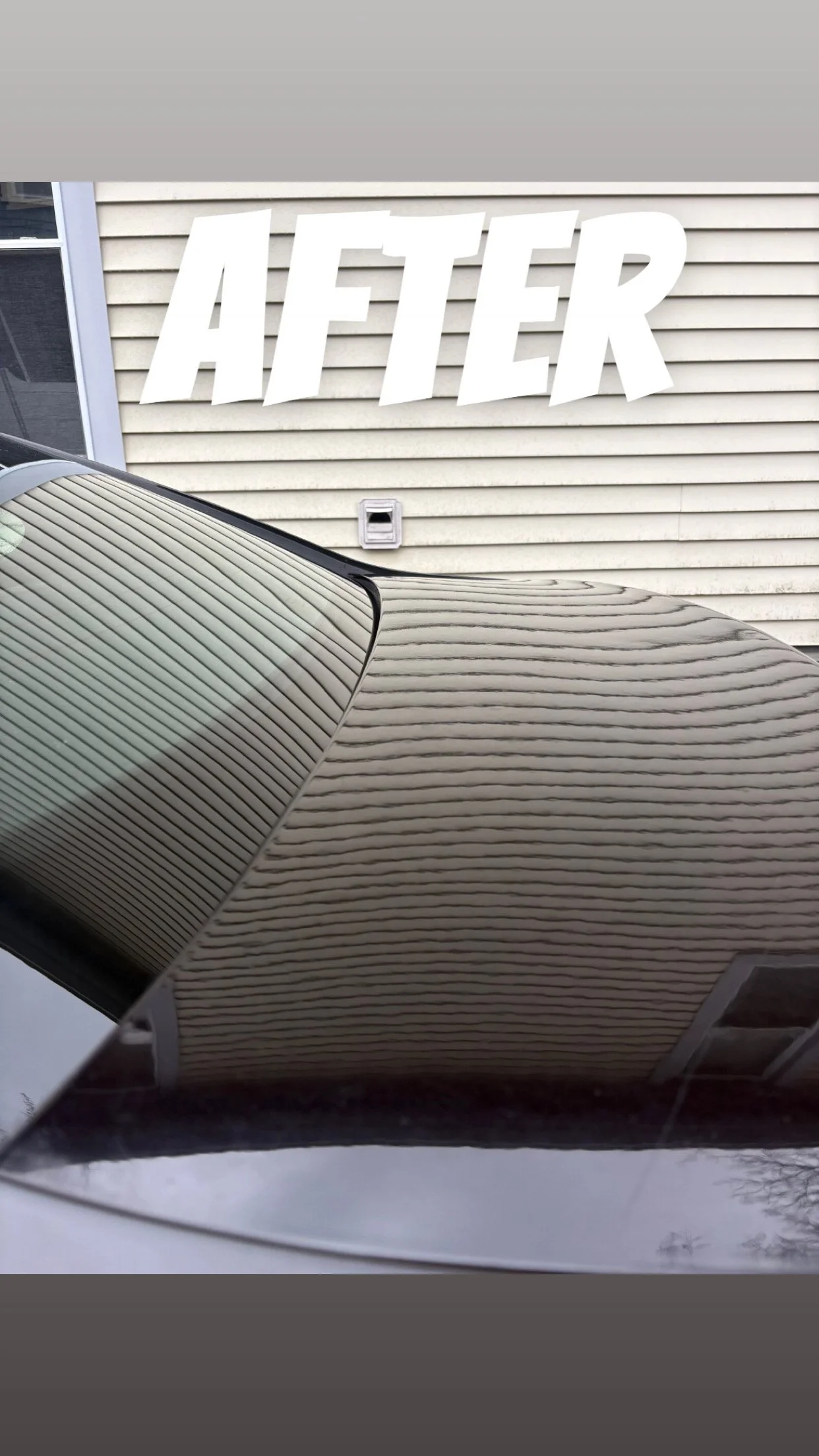 Freshly cleaned truck of a car parked in front of a house with beige vinyl siding and a window.