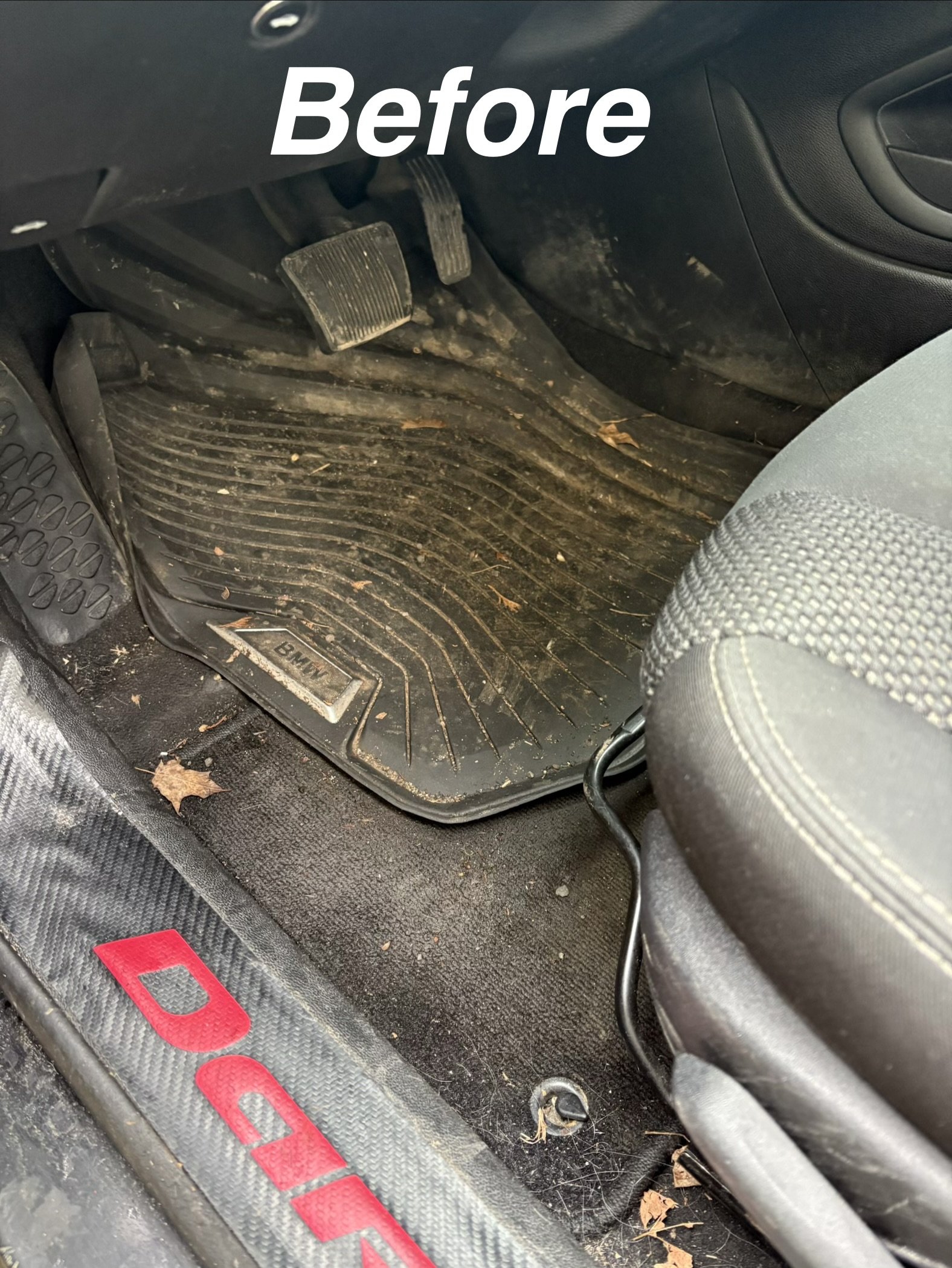 Dirty car floor mat and pedals inside a vehicle, with debris and leaves scattered around.