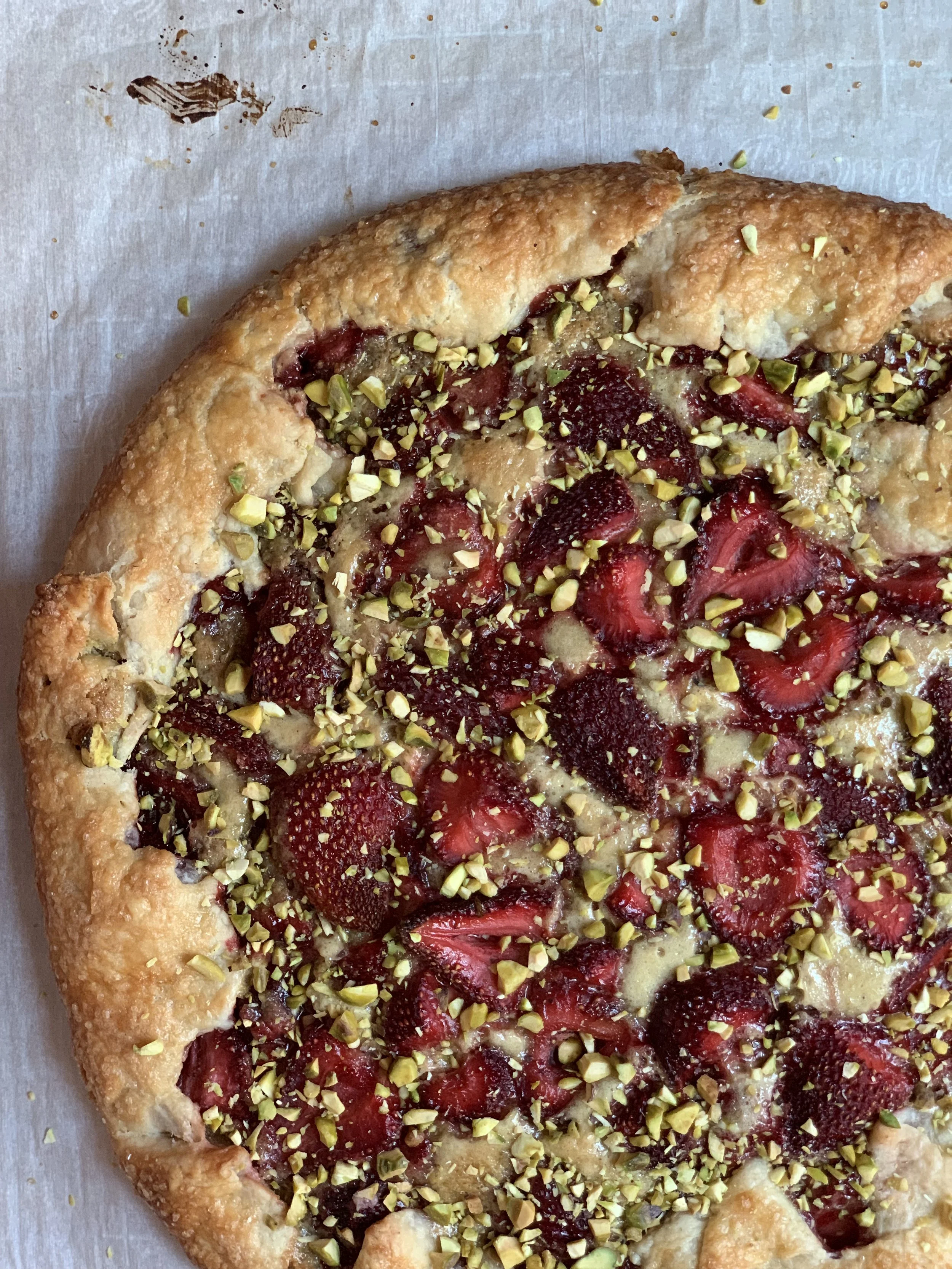 A fruit tart with sliced strawberries and chopped pistachios on top