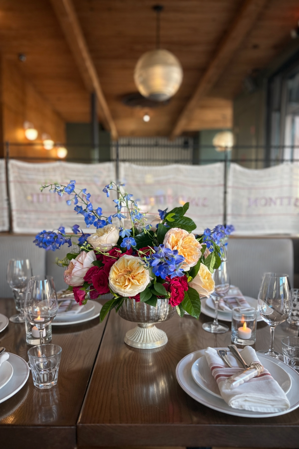 Flowers arranged on a set dining table in a warm wood interior.