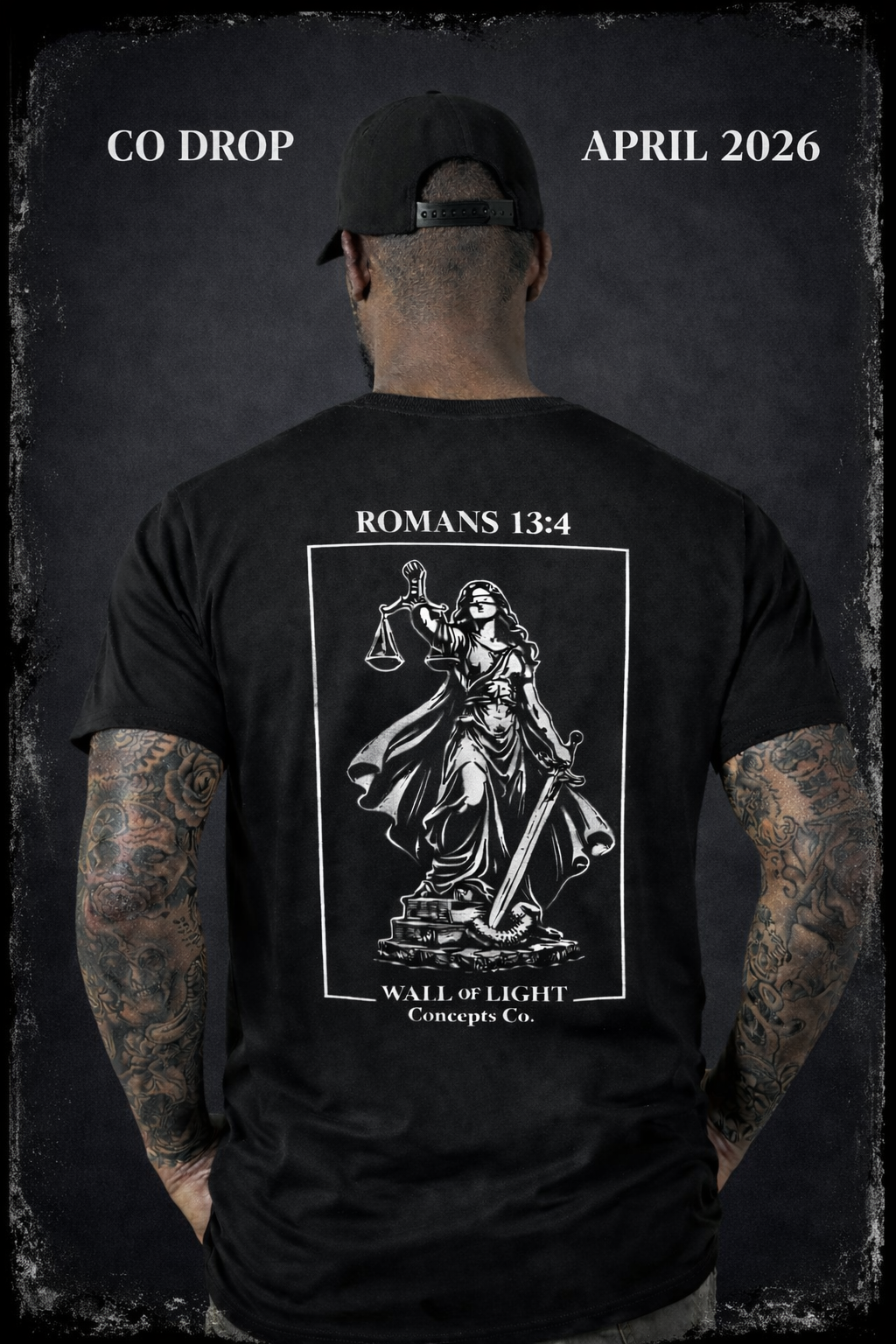 Back of a man wearing a black baseball cap and a black T-shirt with a graphic of Lady Justice holding scales and a sword, with text referencing Romans 13:4 and a concept named "Wall of Light" from Concepts Co. The man has tattoos on both arms.