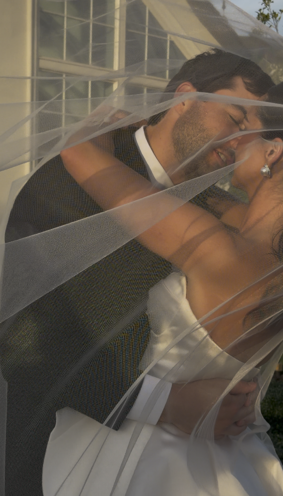 A newlywed couple embracing and smiling through a sheer wedding veil. Love Letty Content, Luxury Wedding Content Creation in Dallas Texas.