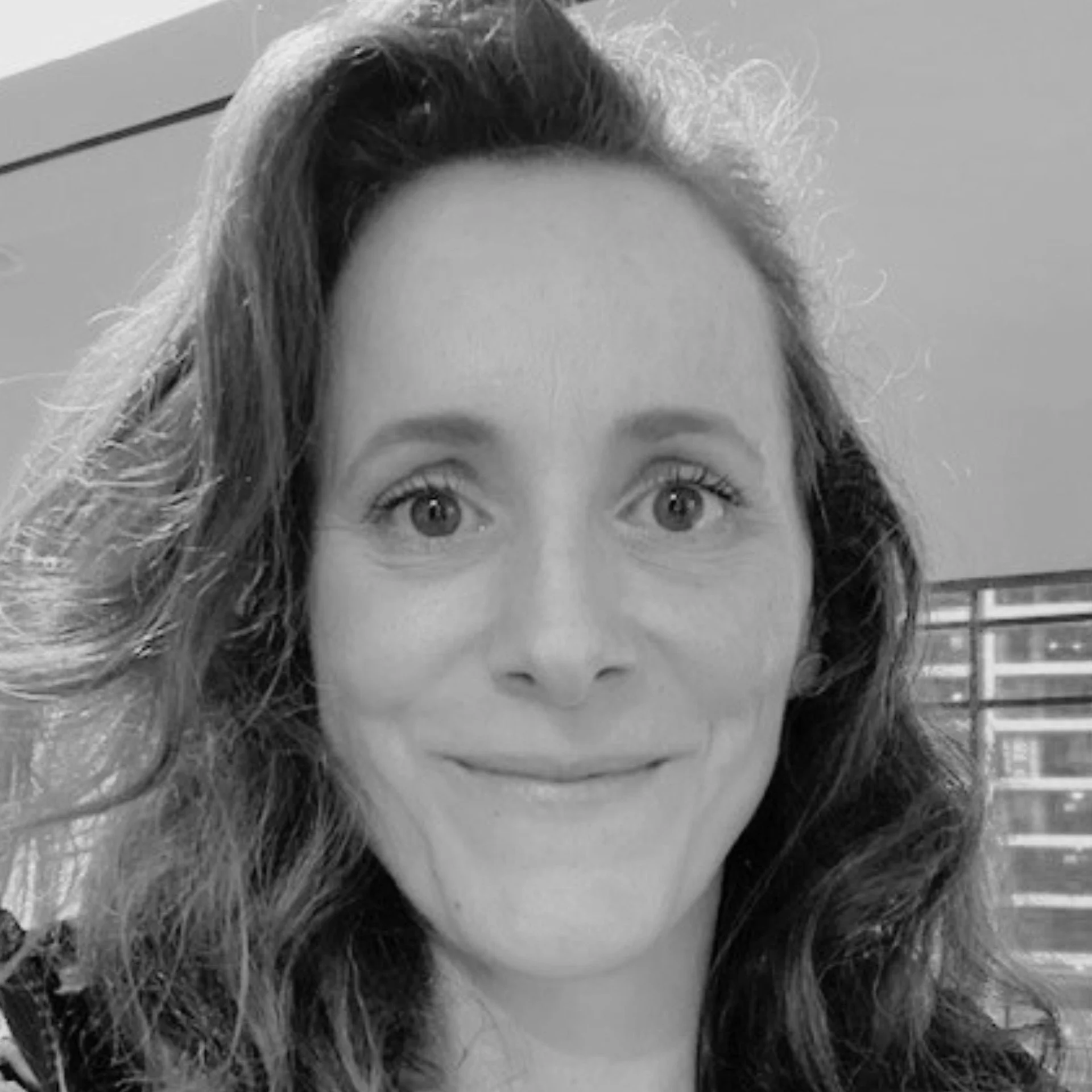 Close-up black and white photo of a woman's face showing her eyes, nose, and lips, with curly hair partially covering her forehead.