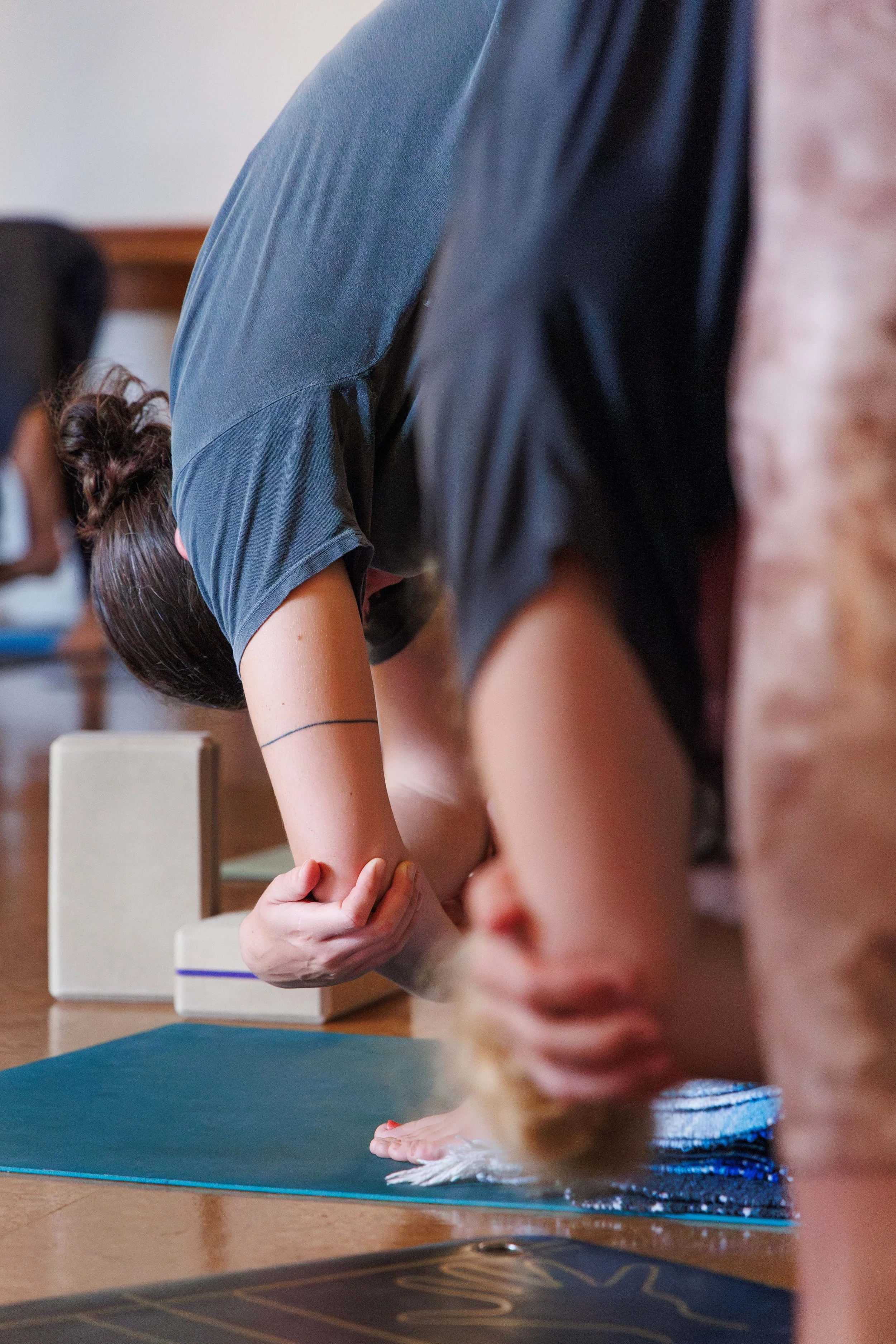Woman in forward fold holding elbows in a yoga class