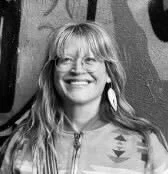 Black and white photo of a woman with long hair and glasses, smiling.