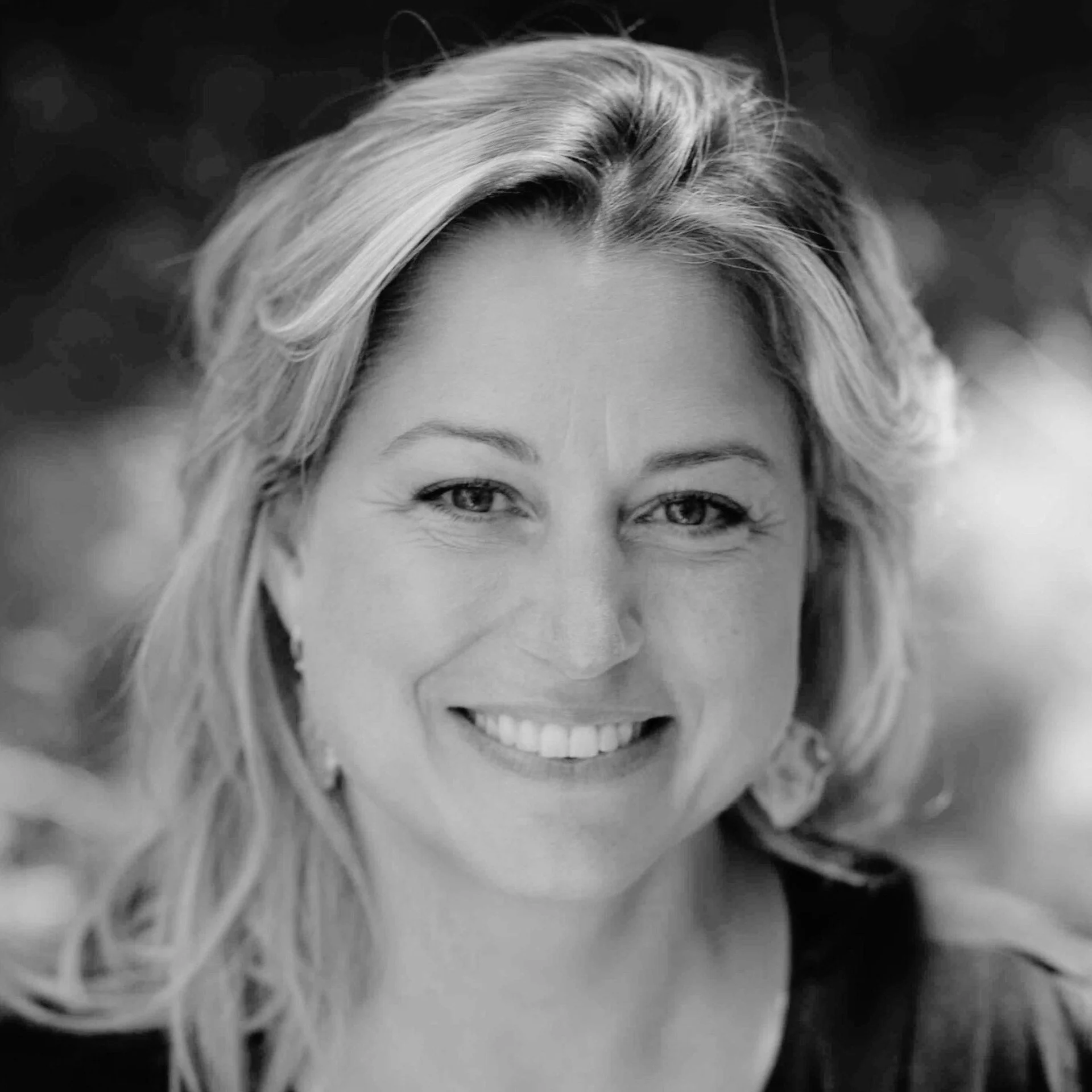 Close-up black and white photo of a person's face, highlighting the eyes, forehead, and hair, with a blurred background.