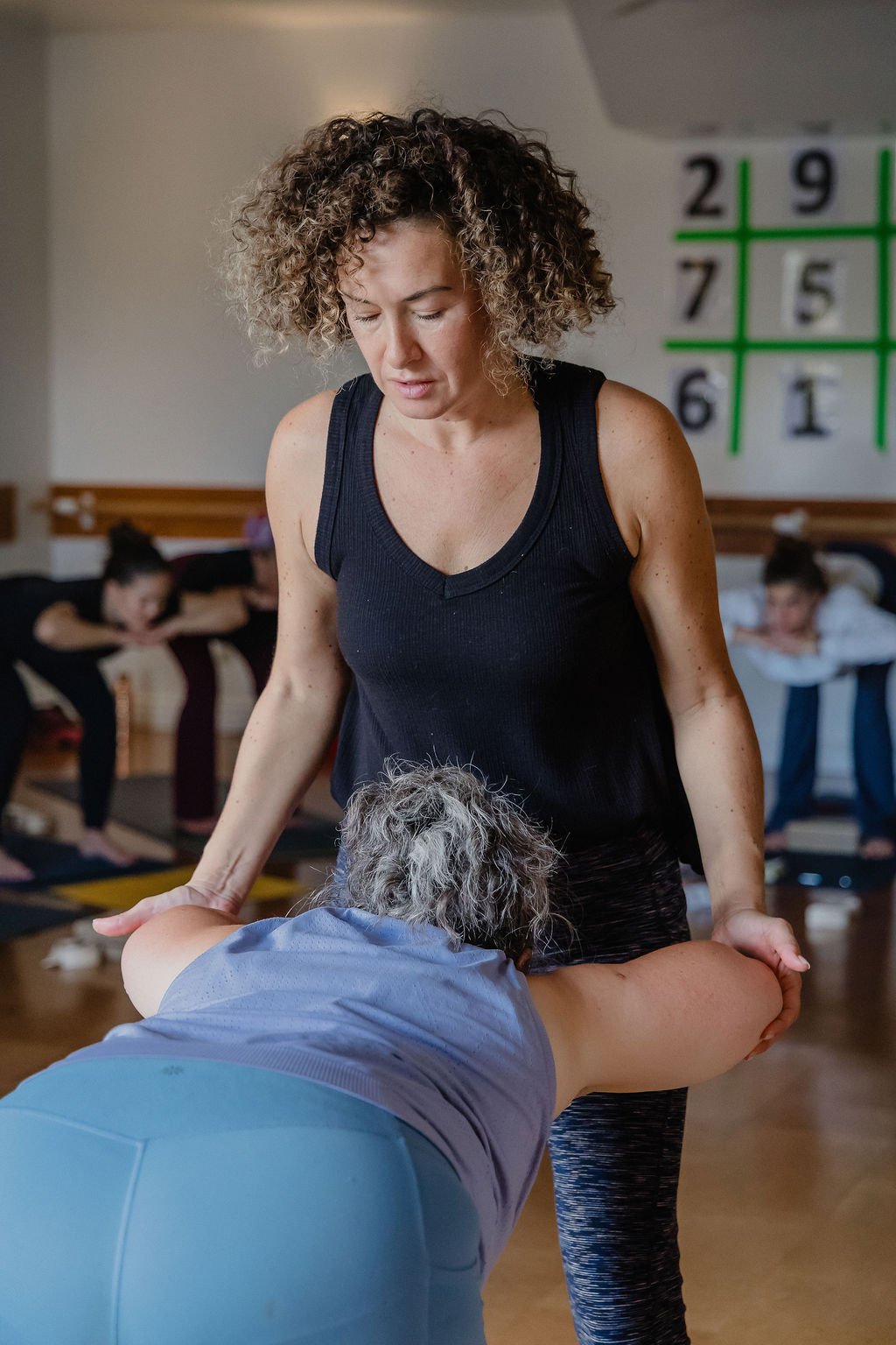 Yoga teacher giving a hands-on assist in a Katonah class