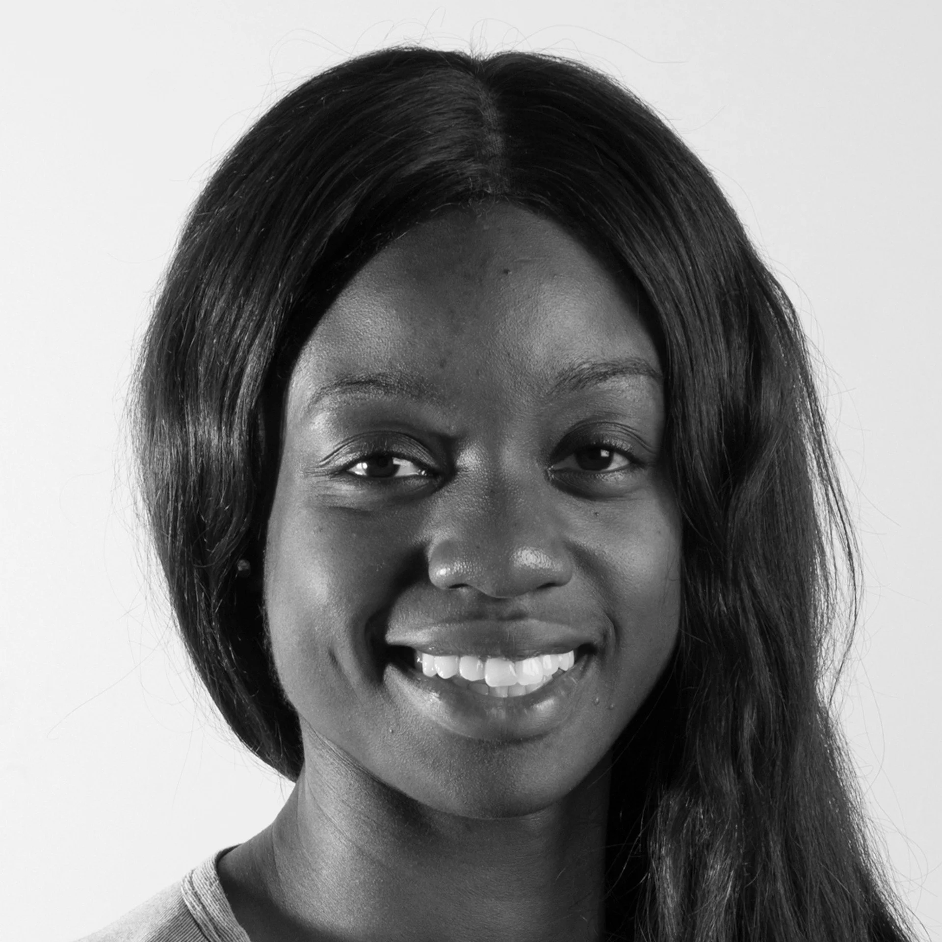 Close-up black and white photo of smiling woman with dark hair, showing her eyes, nose, and mouth.