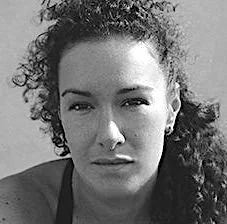 Close-up of a woman with curly hair, looking serious, in black and white.
