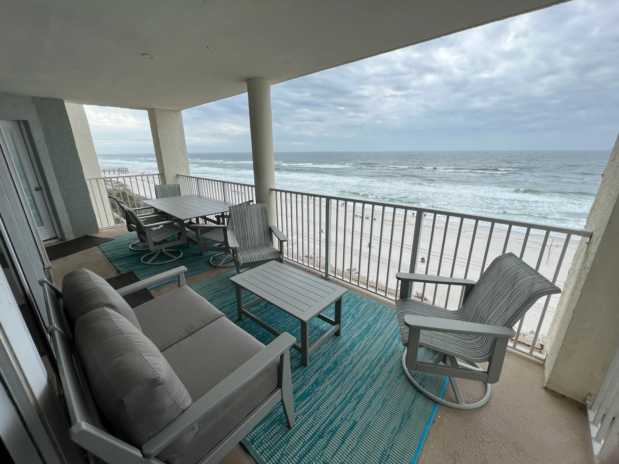 Balcony view with outdoor furniture overlooking the ocean and cloudy sky.
