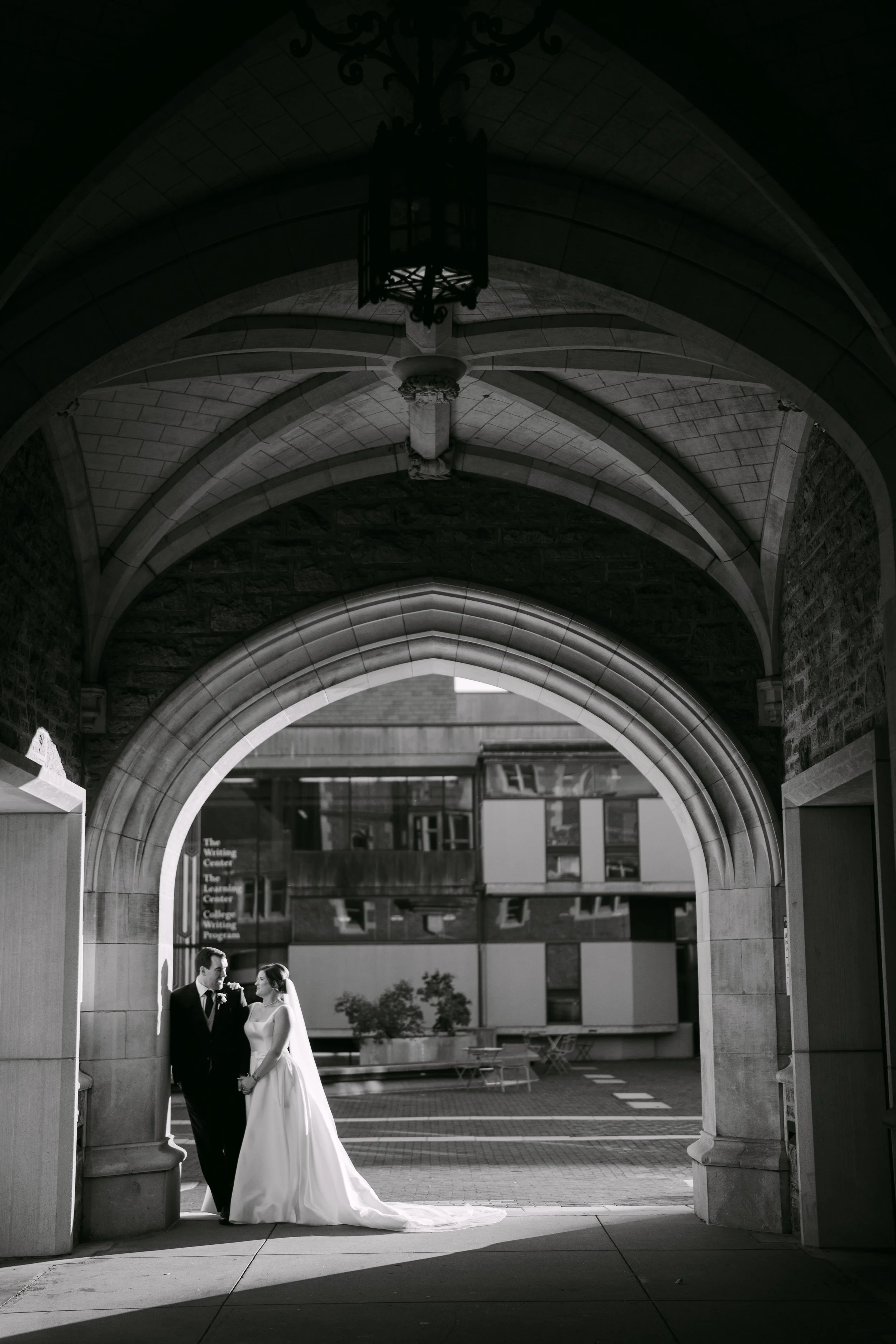 married couple under an archway leading through a facade into an open street, couples wedding photography