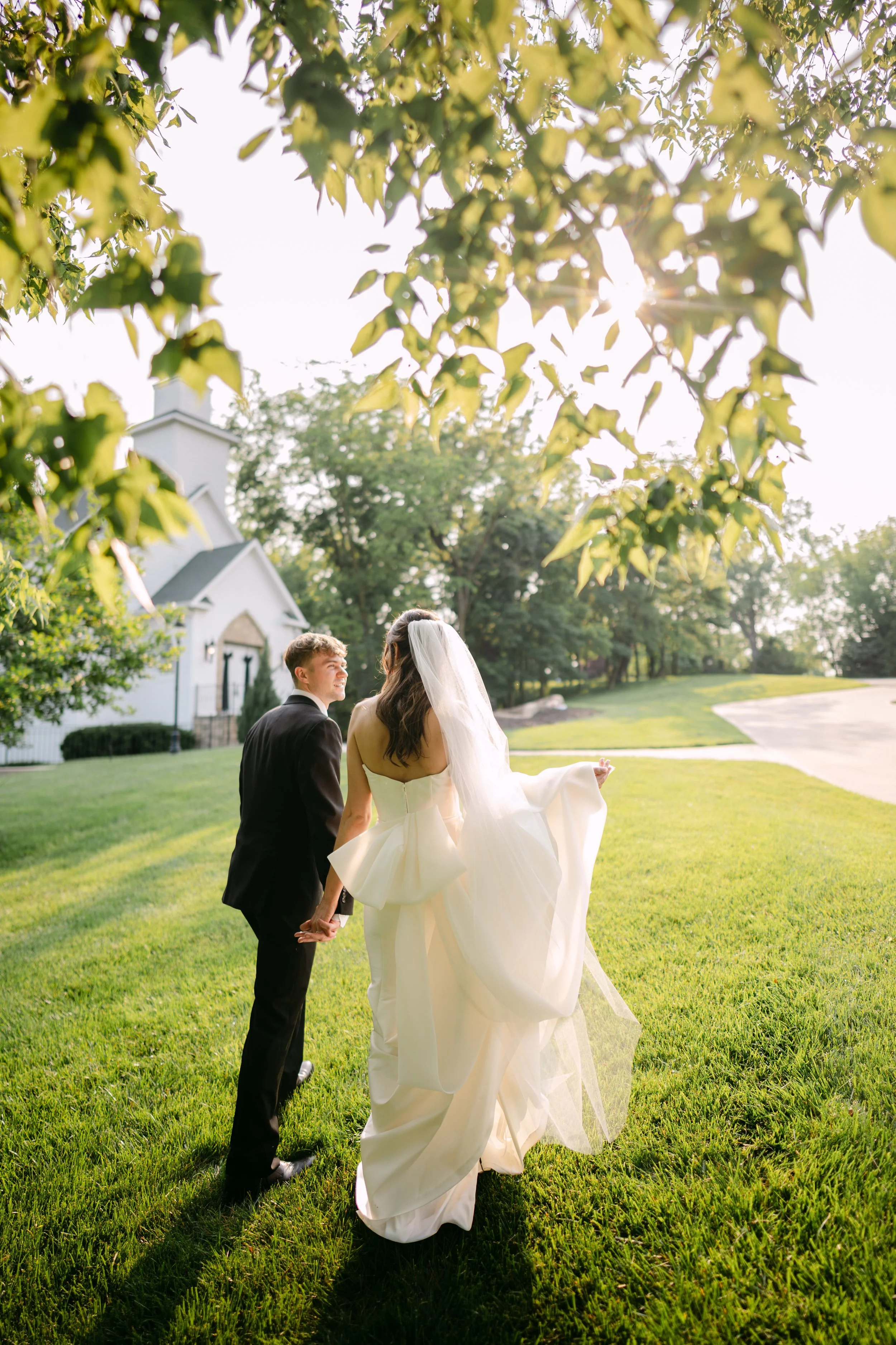A married couple holding hands outside of a chapel in the light of golden hour