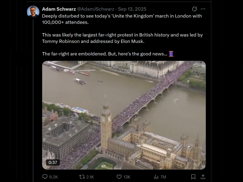 An aerial view of a large crowd gathered on a bridge over the River Thames in London, with Big Ben and surrounding buildings in the background.