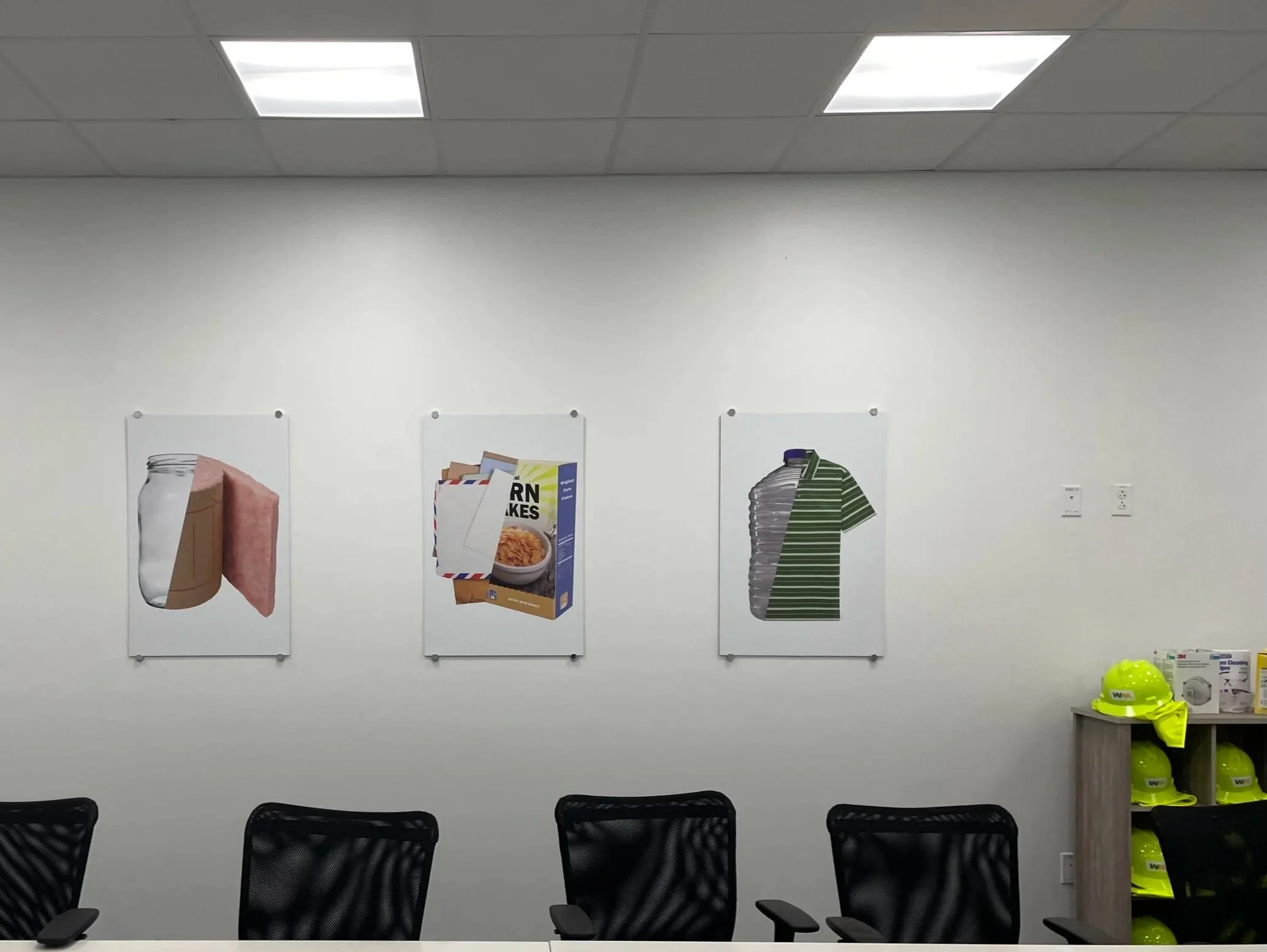 Three posters on a white wall depict a jar with a piece of cardboard and pink insulation, a cereal box with an letter envelope, and a stack of water bottles with a green striped shirt layered over them.