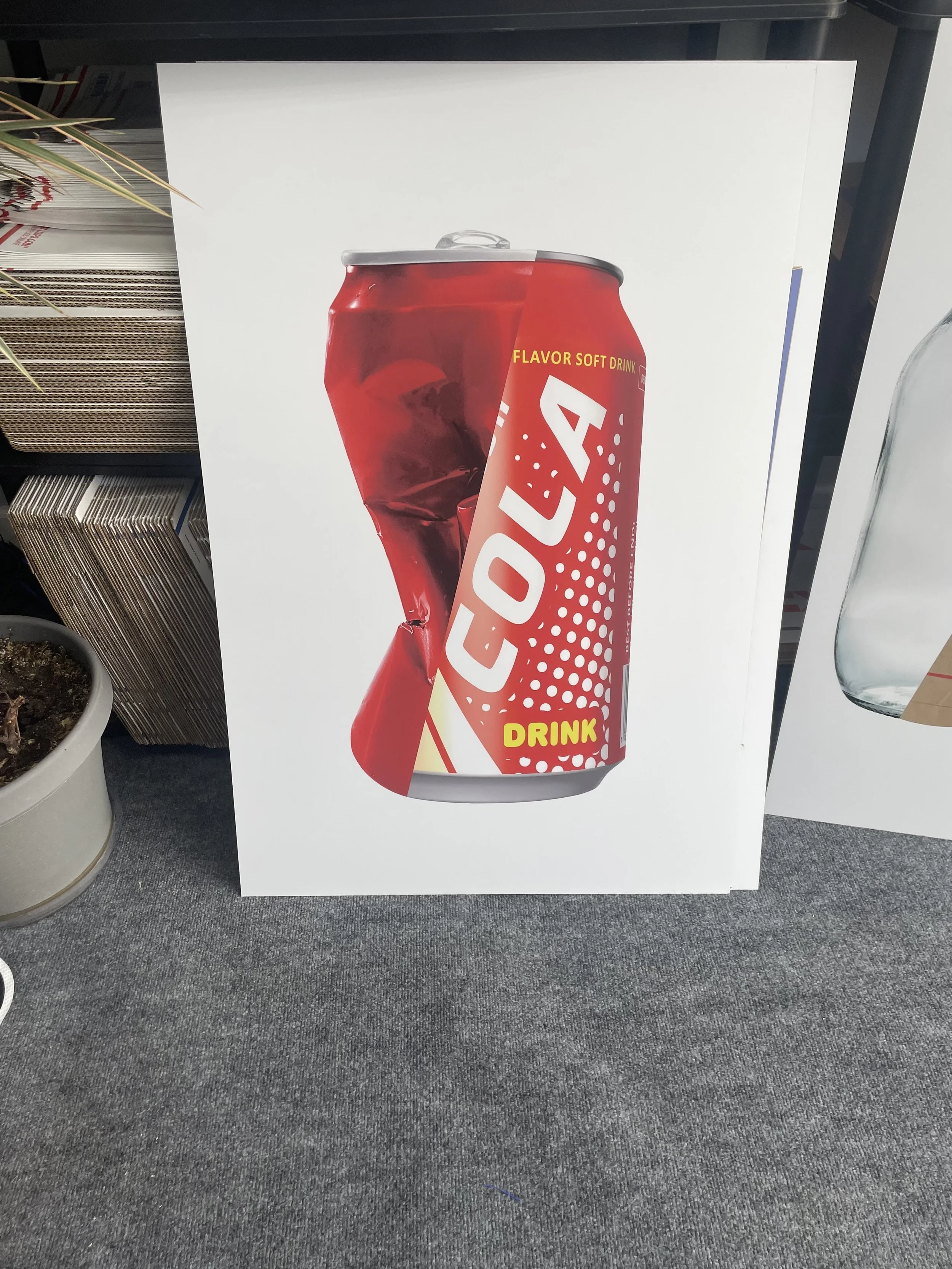 A poster with a red Coca-Cola can that has a dent in it, with the words "Coca-Cola" and "Drink" visible. The can is shown with some ice cubes inside, and the background is plain white.