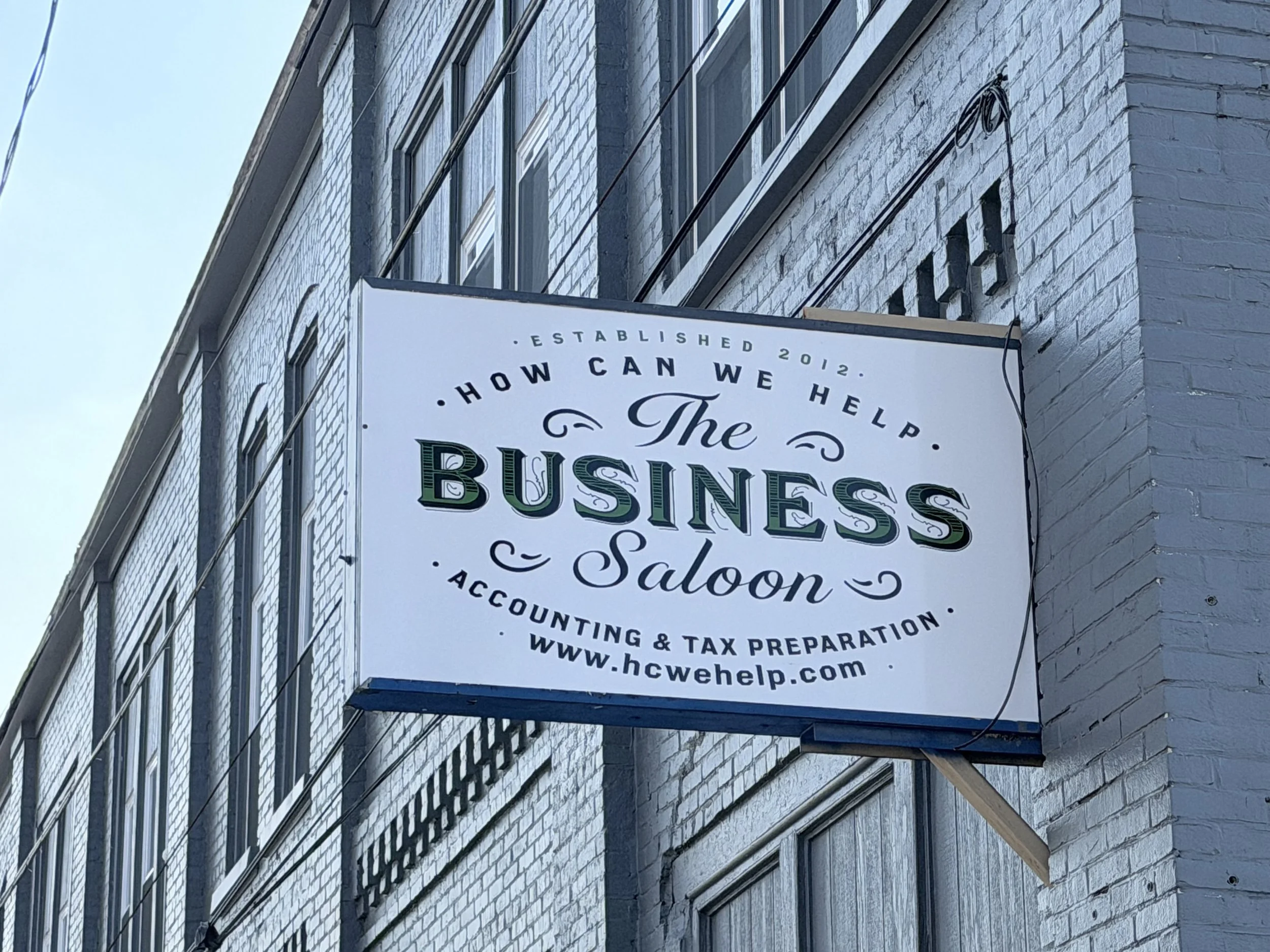 Sign for The Business Saloon, an accounting and tax preparation service, mounted on a brick building.