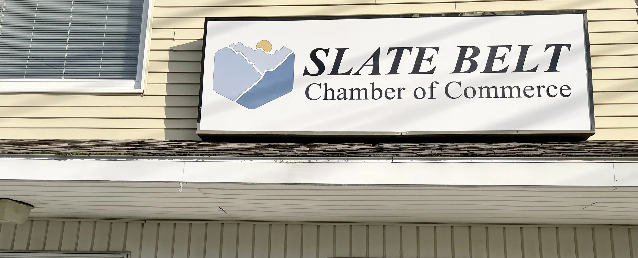 Signboard for Slate Belt Chamber of Commerce mounted on a beige building with a window above.