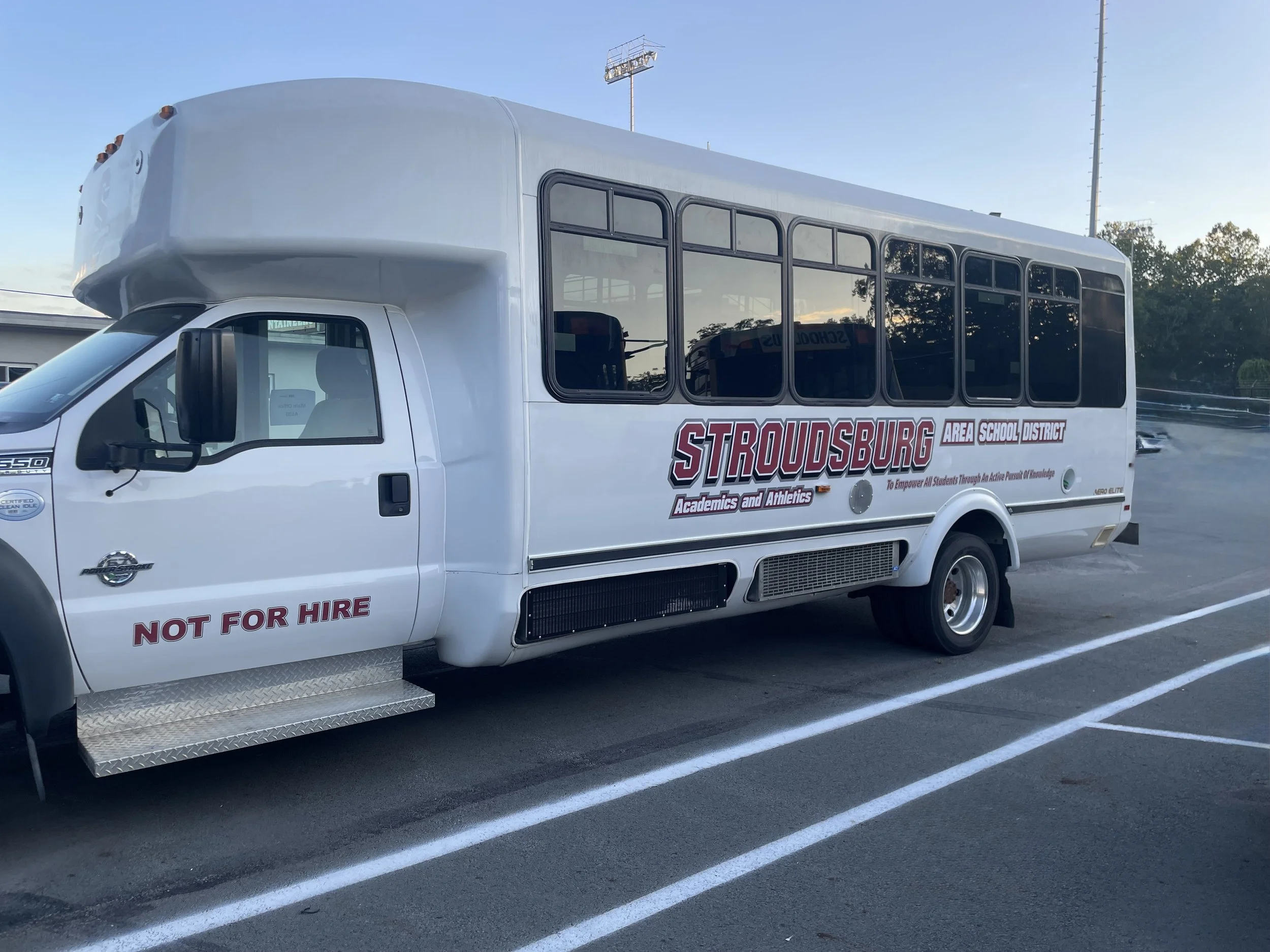 White school bus with Stroudsburg Area School District logo parked in a lot, with 'NOT FOR HIRE' written on the front door and large tinted windows along the side.