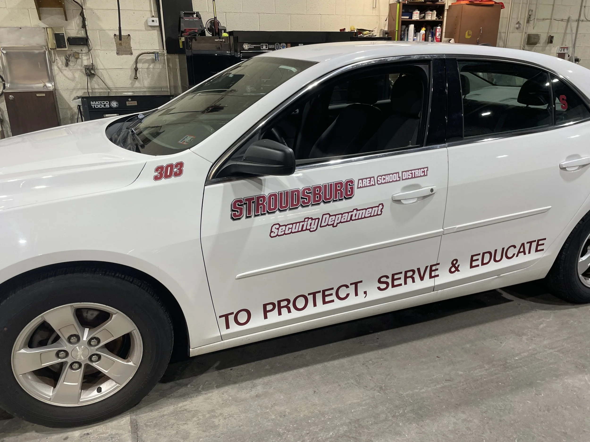 White police car with markings for Stroudsburg Area School District Security Department, parked in a garage.
