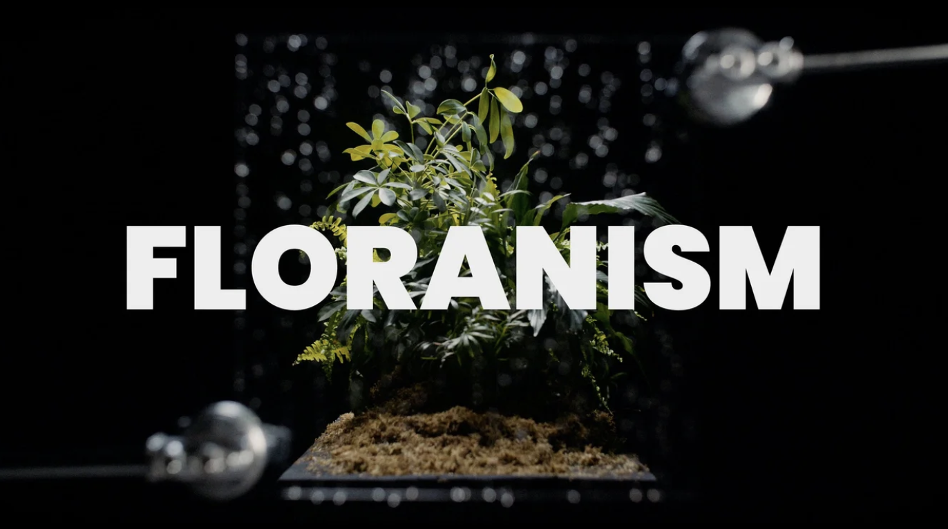 A plant inside a glass terrarium with the word 'FLORANISM' overlayed in large white letters.